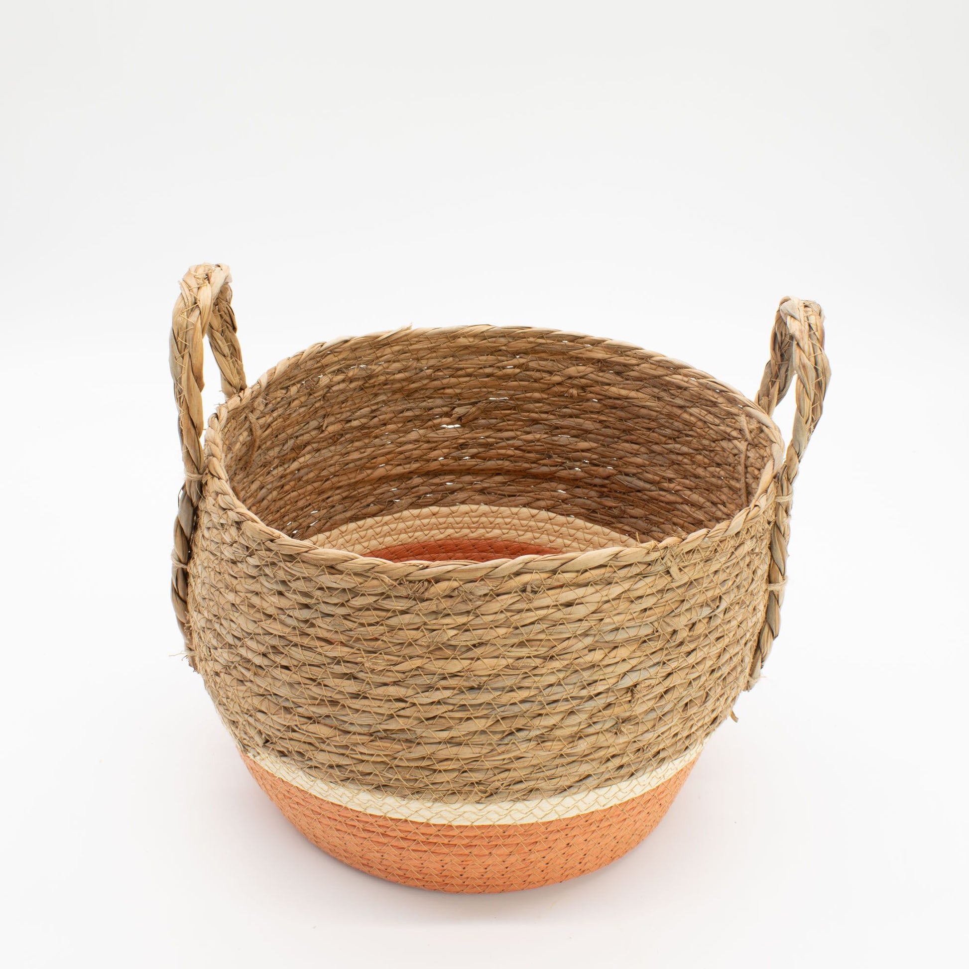 Cesta de pasto marino tejida con asas, tono natural y base naranja, estilo rústico artesanal sobre fondo blanco.
