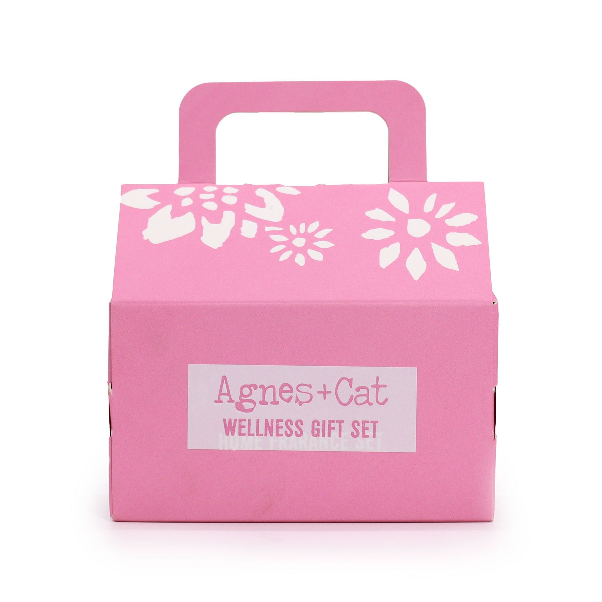 Caja de regalo rosa con asa, diseño floral blanco y etiqueta "Agnes & Cat Wellness Gift Set" al frente.