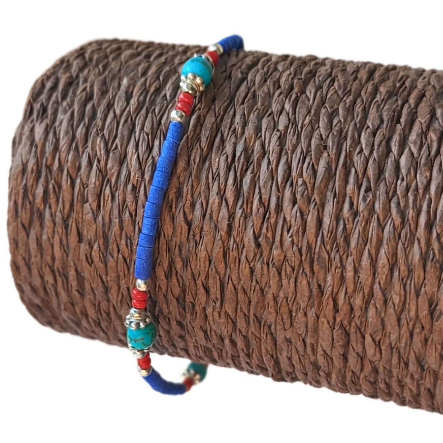 Pulsera de cuentas de cerámica azul, roja y verde con detalles metálicos; estilo bohemio y vibrante.