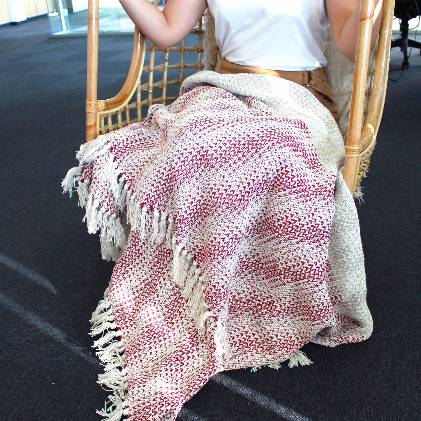 Manta de algodón beige y rojo con diseño de zigzag y flecos, ideal para sofá o silla colgante.