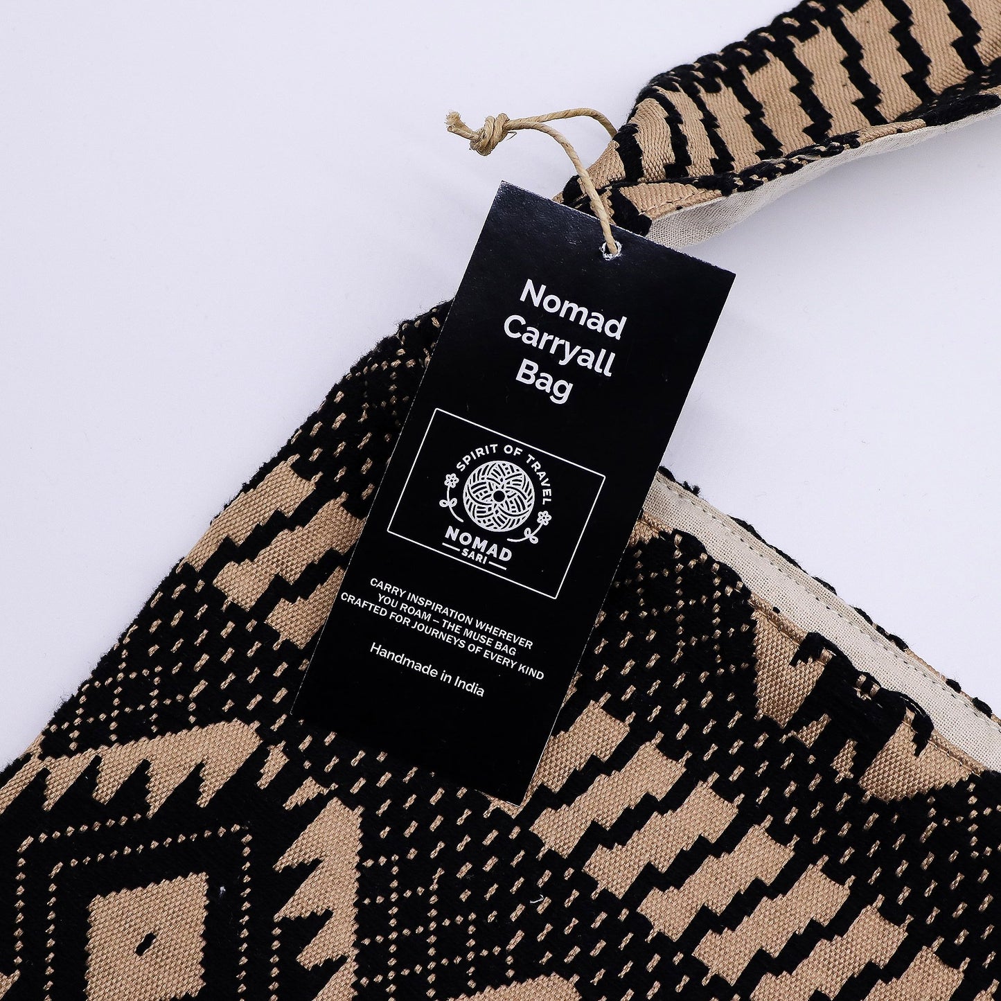Bolsa de mano Nomad, hecha a mano en India, en tonos negro y beige con diseño geométrico y asas resistentes.