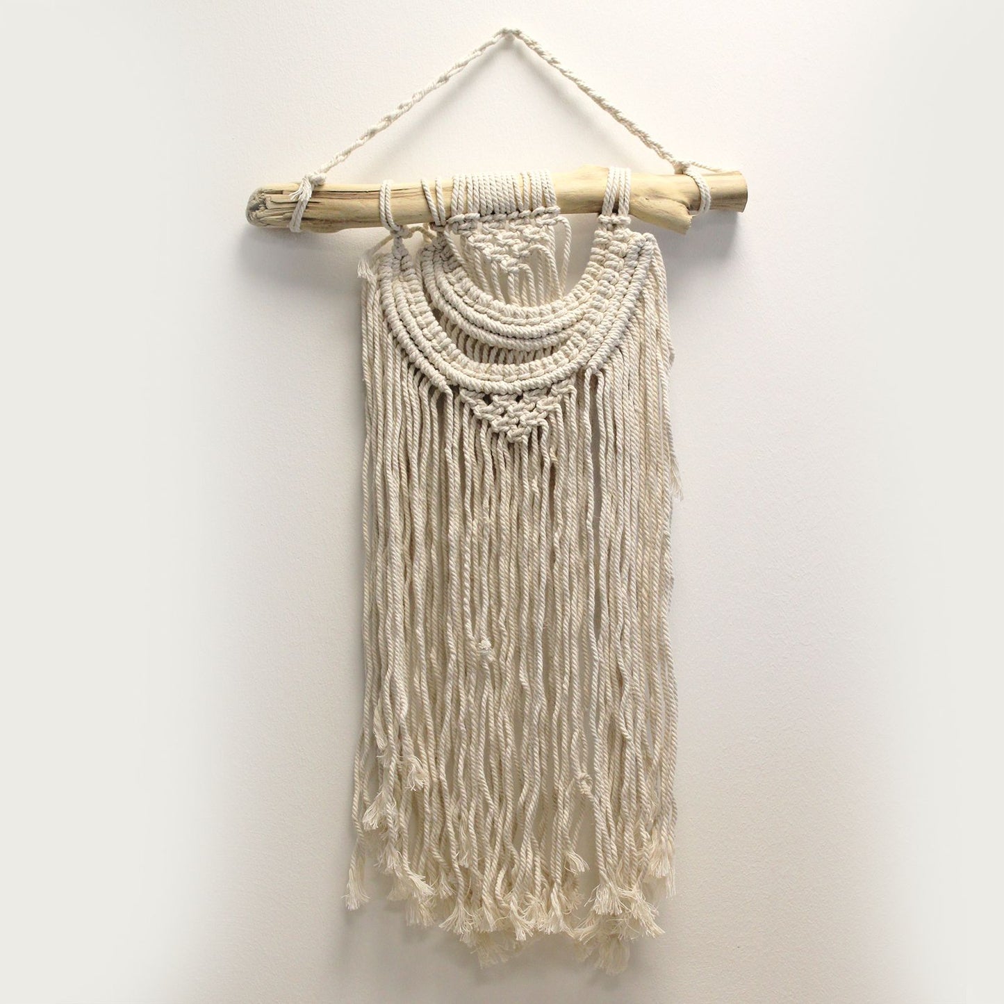 Tapiz de macramé beige con flecos, colgado en una barra de madera. Decoración bohemia para paredes.