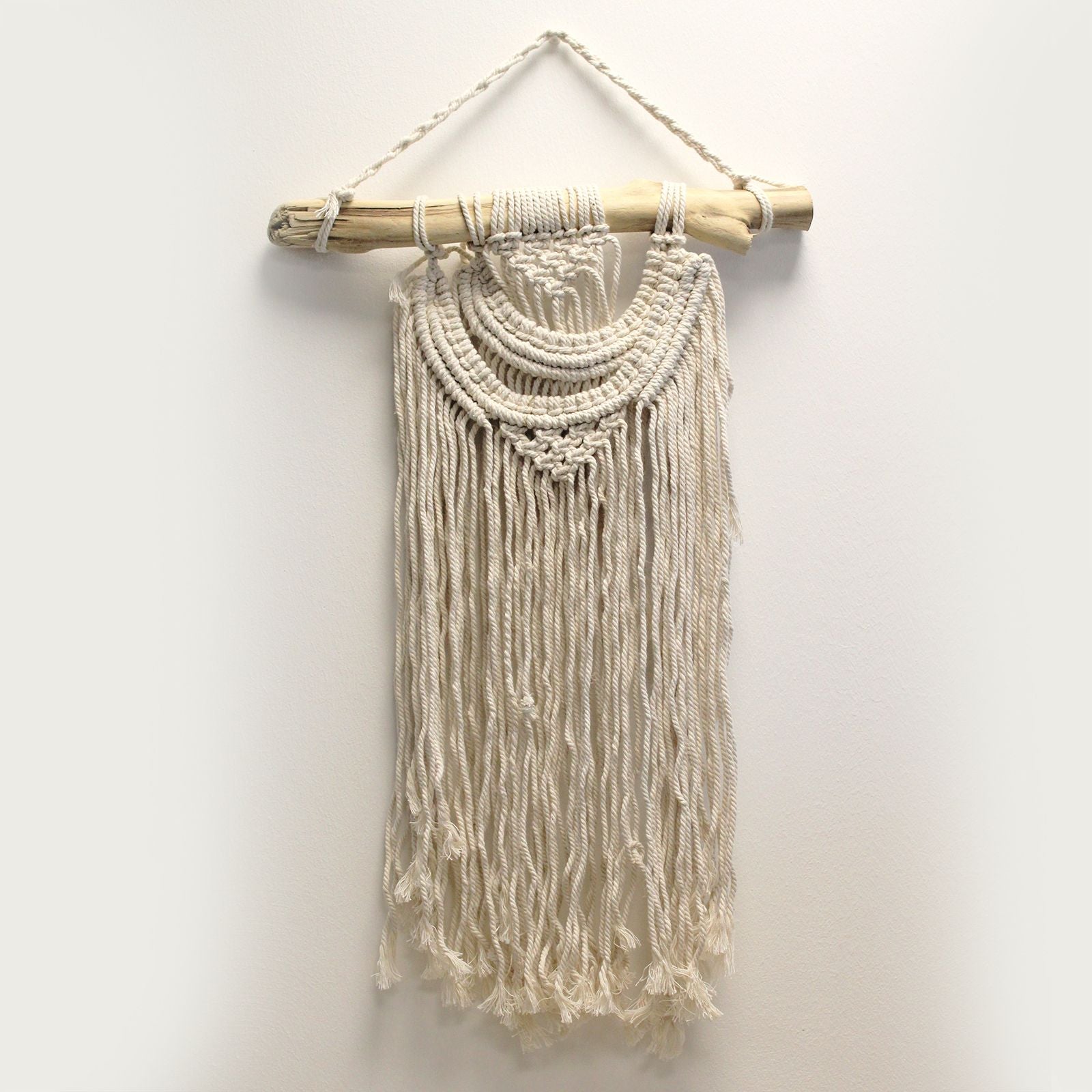 Tapiz de macramé beige con flecos, colgado en una barra de madera. Decoración bohemia para paredes.