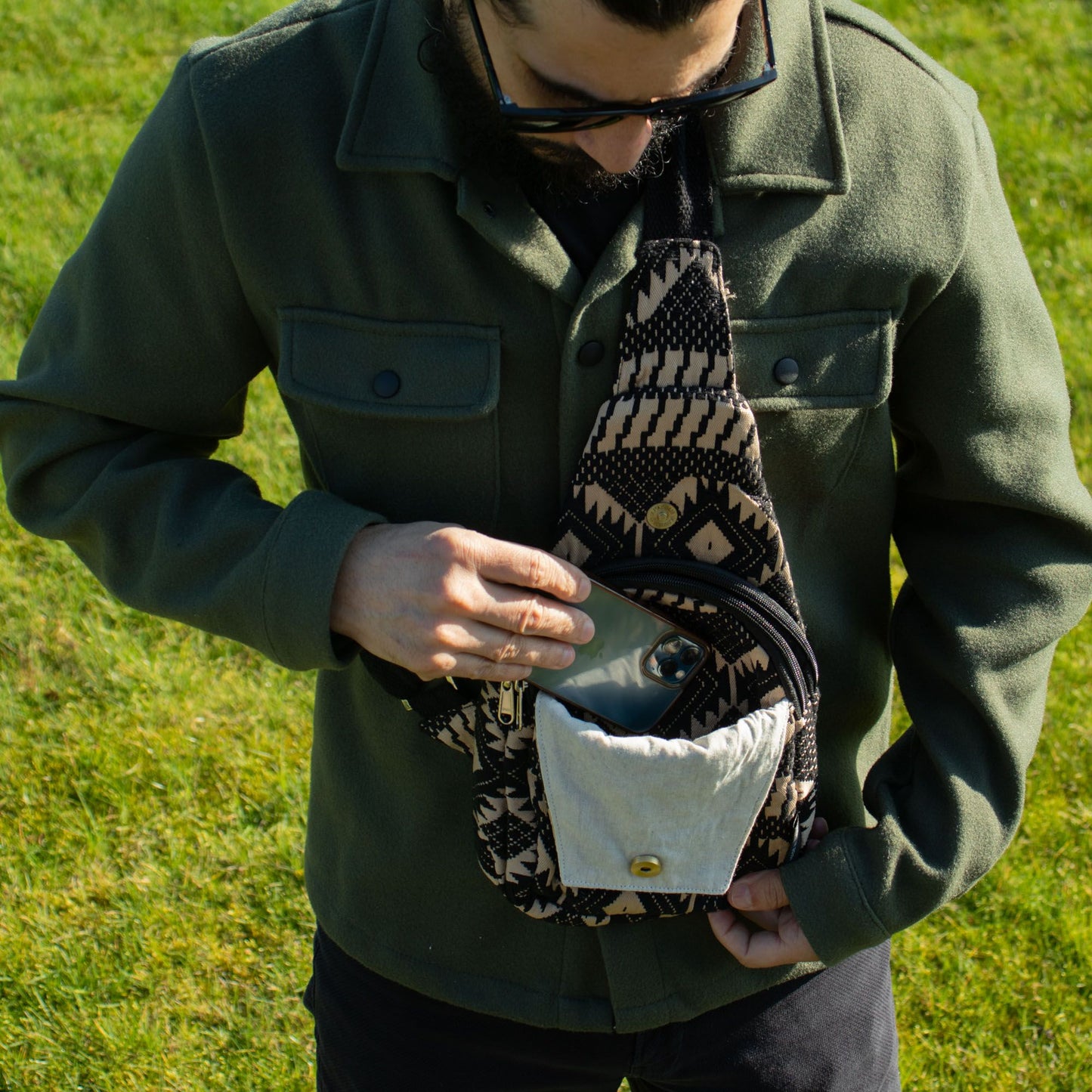 Mochila tipo bandolera negra con estampado étnico y detalles en beige, ideal para el uso diario y actividades al aire libre.
