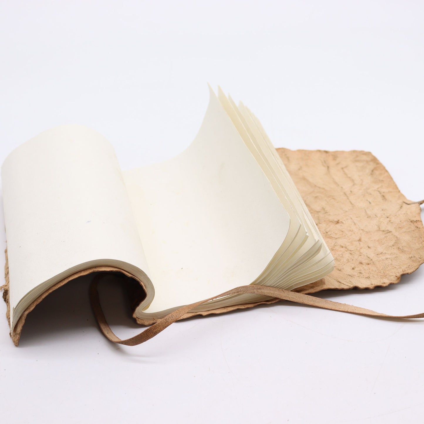 Cuaderno artesanal con cubierta de papel reciclado, páginas en blanco y encuadernación en cuerda marrón claro.