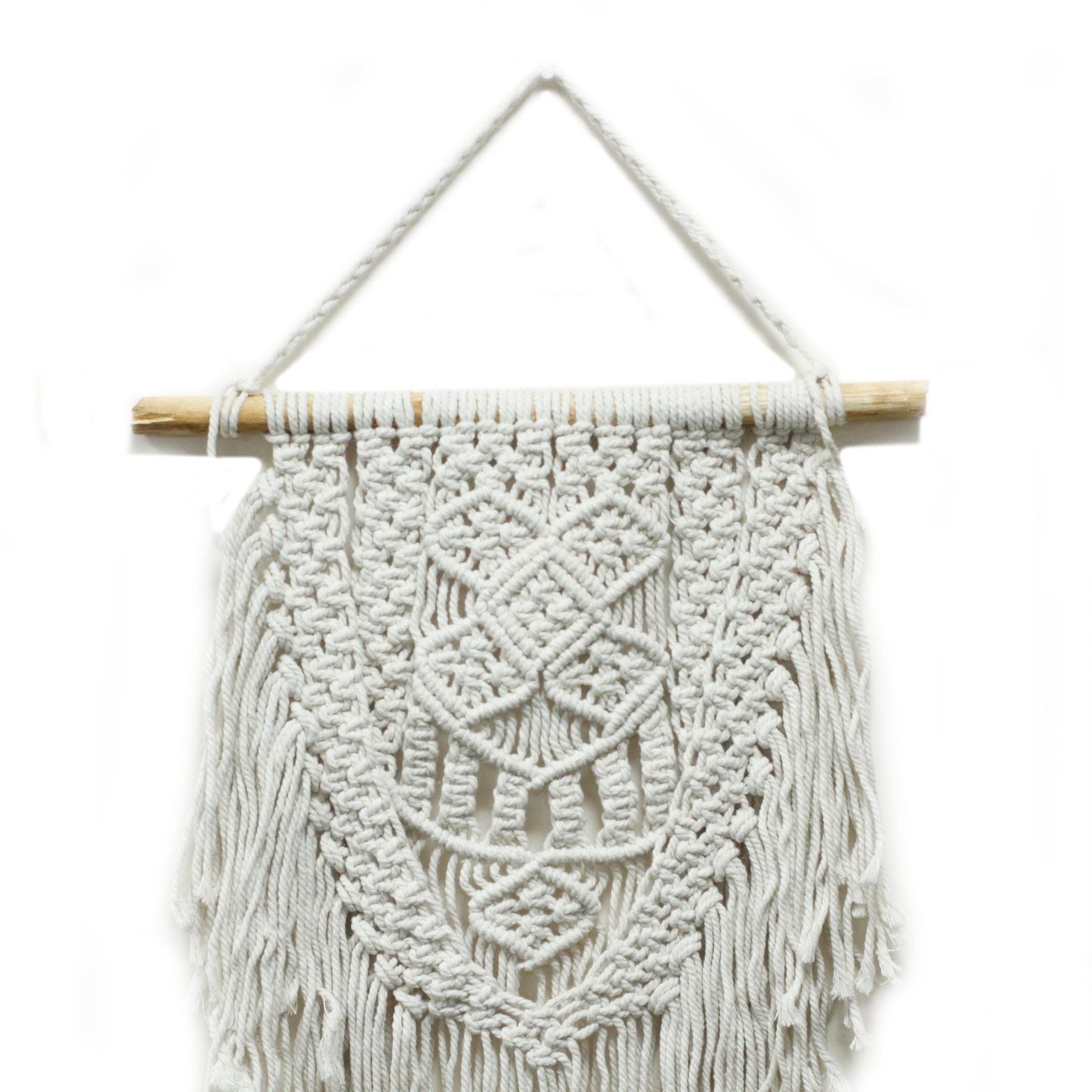 Tapiz de macramé blanco con diseño geométrico y flecos, colgado en barra de madera natural. Perfecto para decorar paredes.