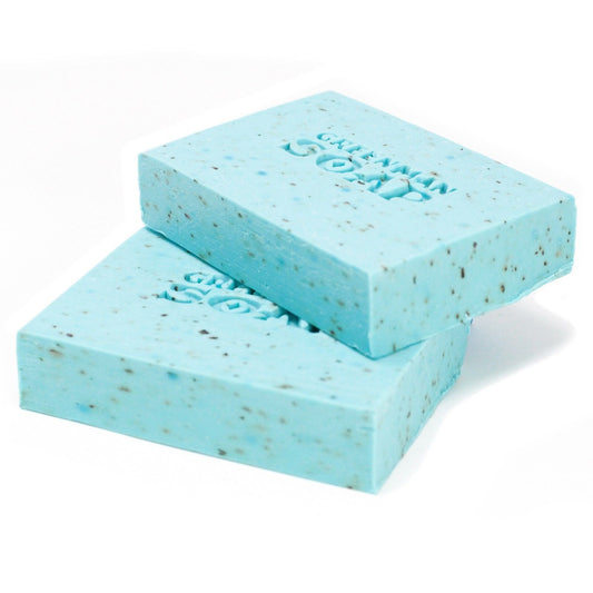 Dos pastillas de jabón azul claro, con motas oscuras y grabado "Greenman Soap" sobre fondo blanco.