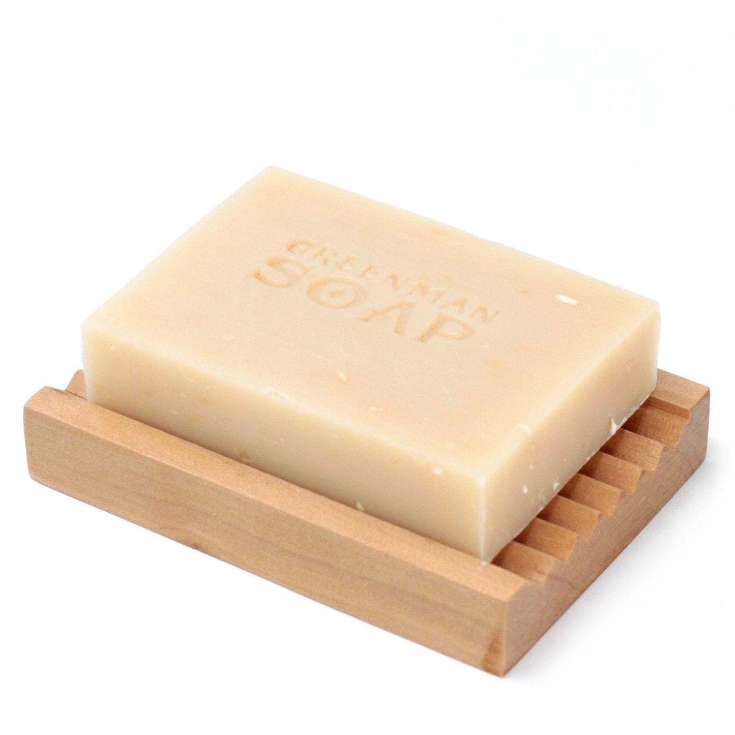 Pastilla de jabón artesanal color crema con "Greenman Soap" grabado, sobre una jabonera de madera clara y ranurada.