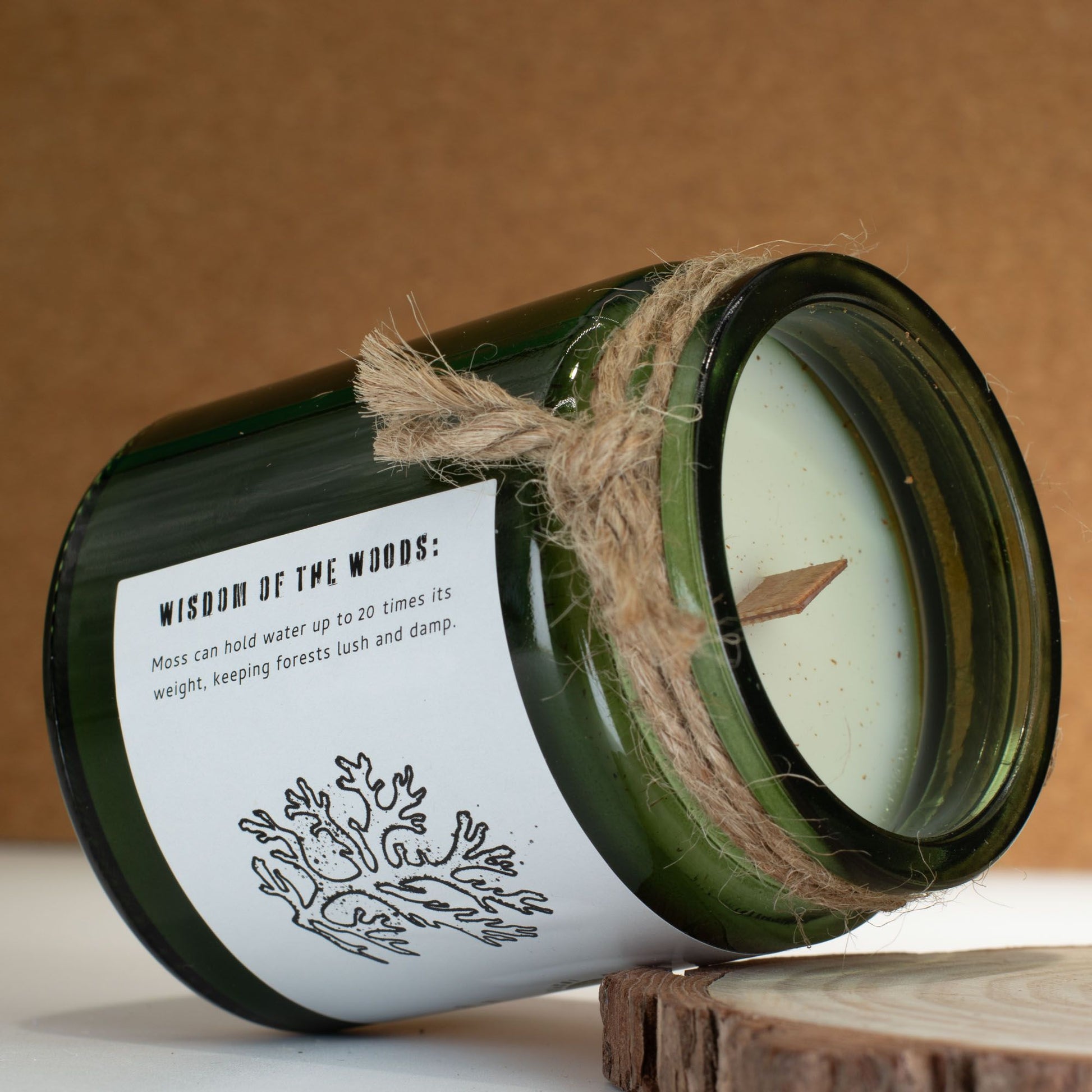 Vela verde de vidrio con aroma a bosque, mecha de madera y etiqueta rústica. Perfecta para decoración natural.