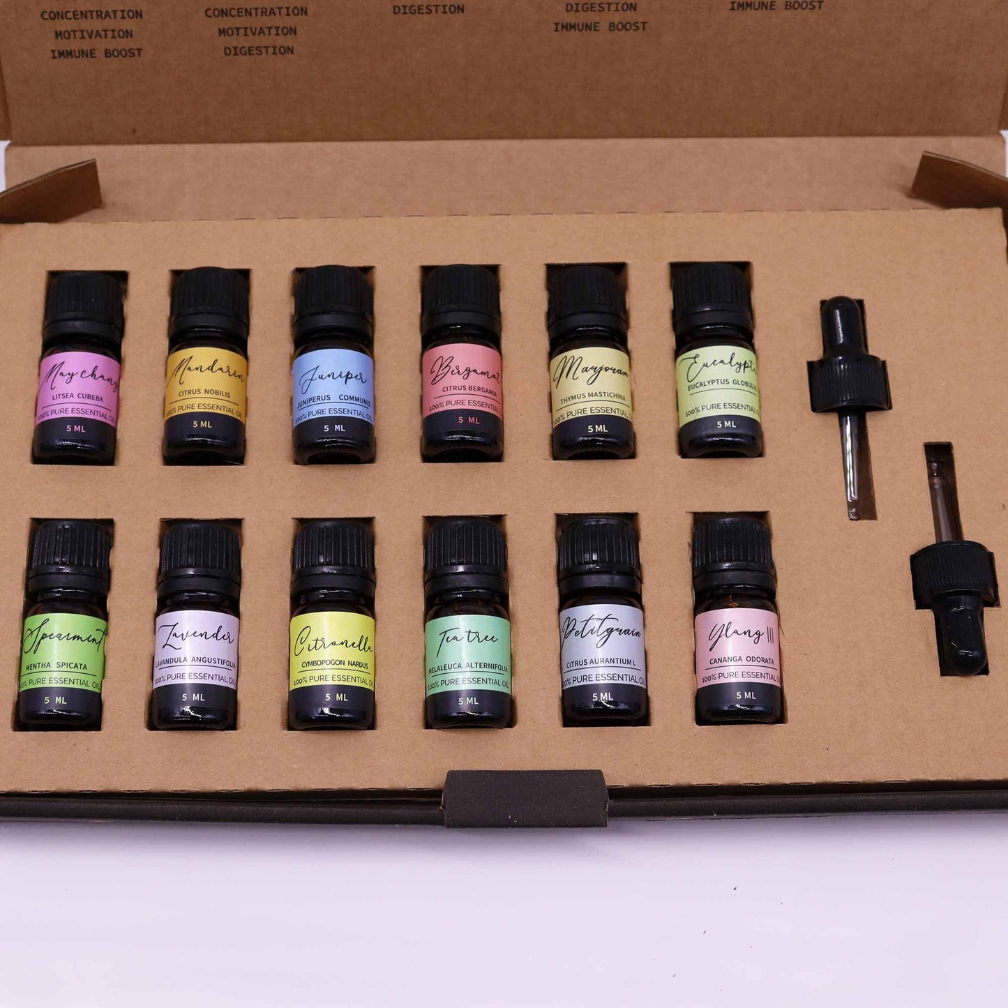Kit de 12 aceites esenciales en frascos de vidrio negro, con etiquetas de colores pastel, presentación en caja marrón.