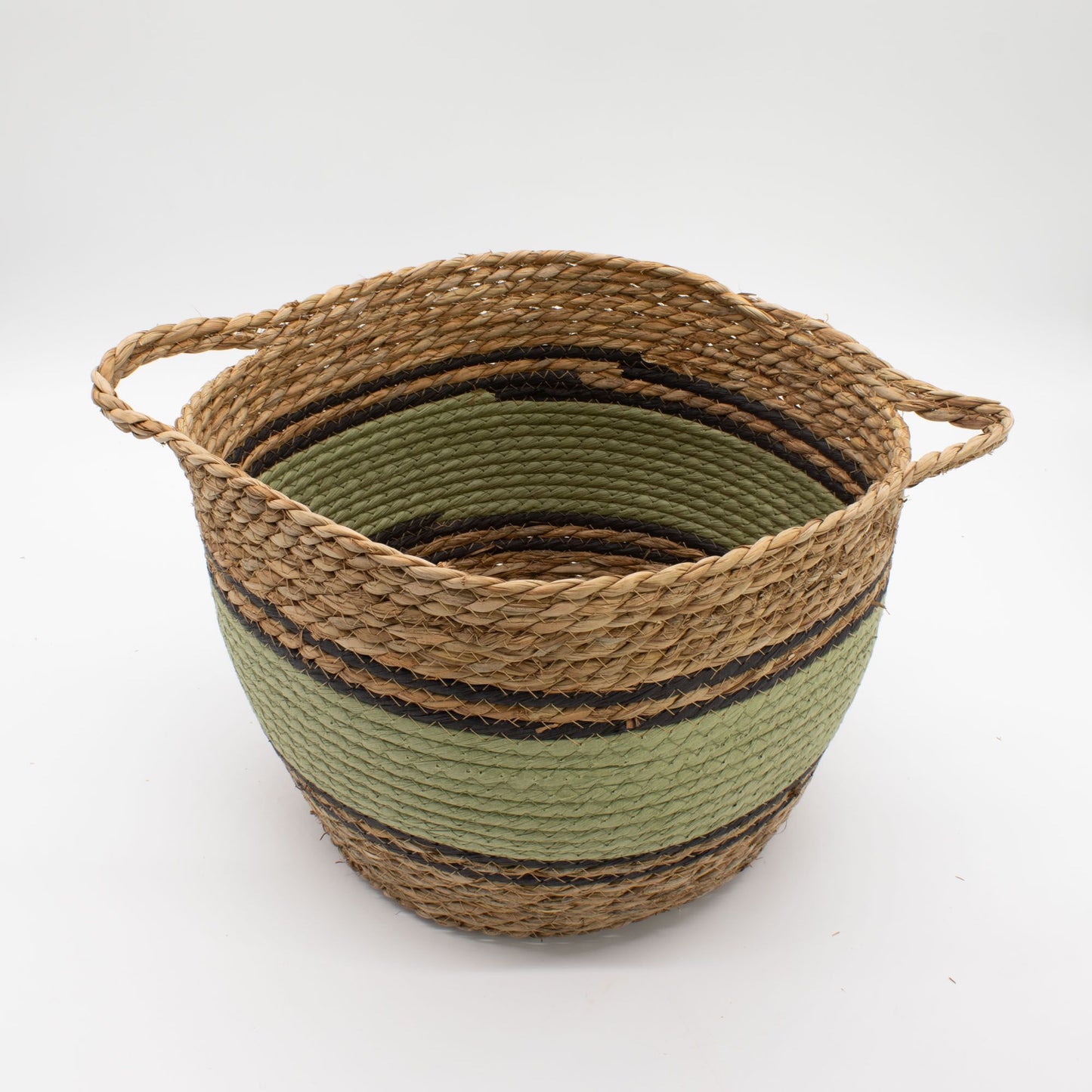 Cesta redonda de fibras naturales, pasto marino y algodón en tonos beige, verde y negro con dos asas laterales.