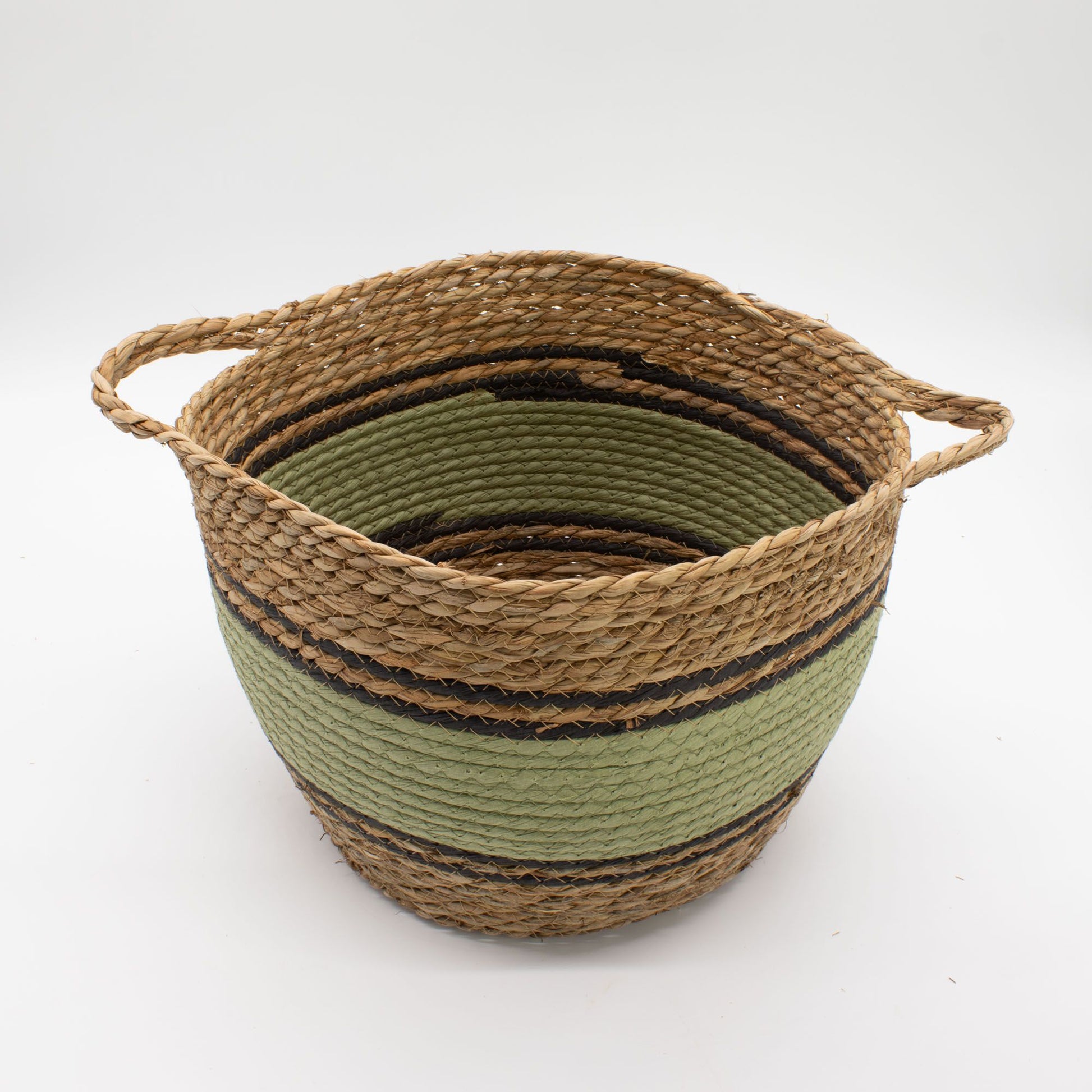 Cesta redonda de fibras naturales, pasto marino y algodón en tonos beige, verde y negro con dos asas laterales.