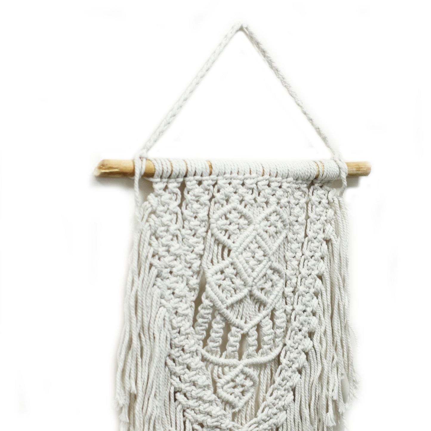 Tapiz de macramé blanco con detalles en trenzado, colgado en una vara de madera. Decoración bohemia para el hogar.