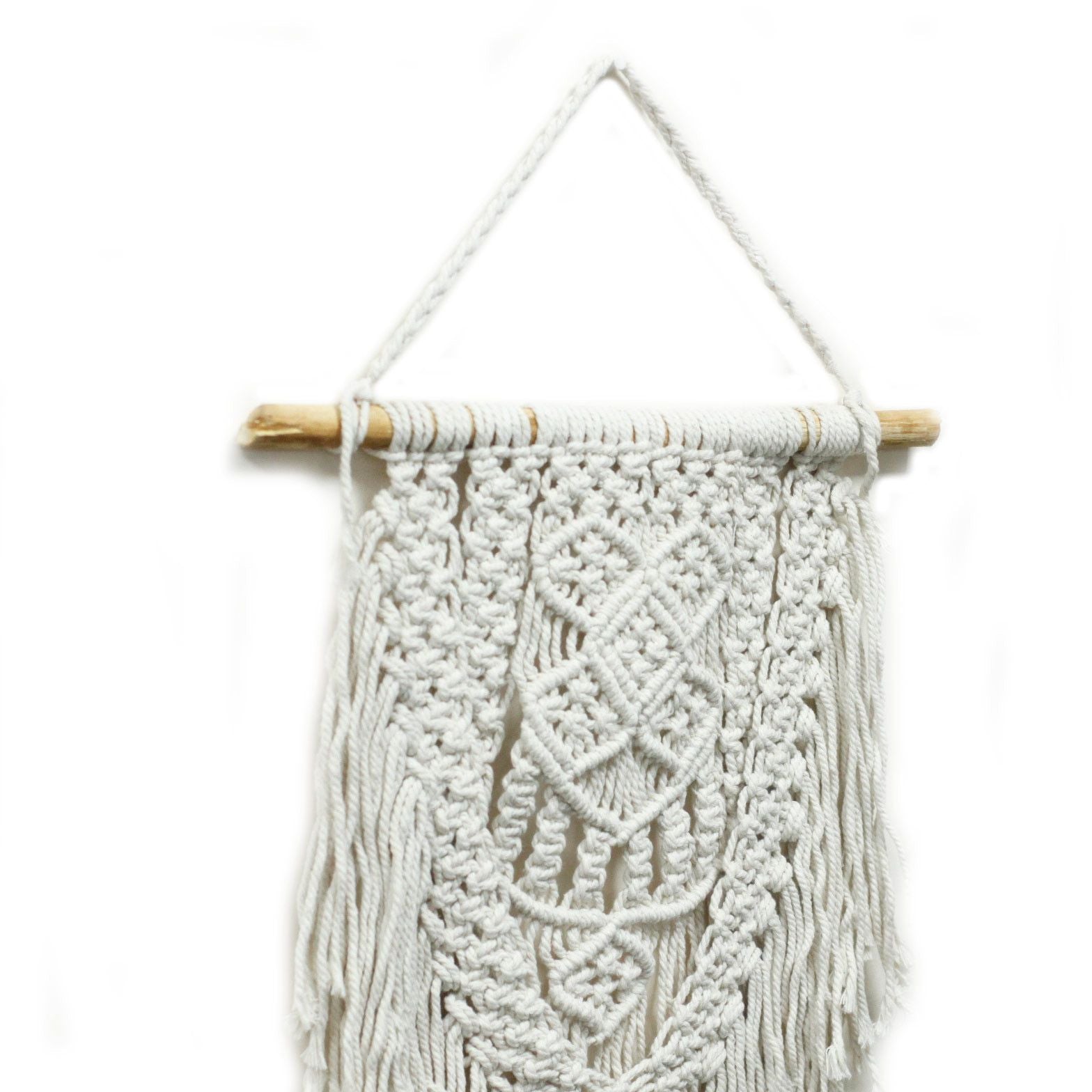 Tapiz de macramé blanco con detalles en trenzado, colgado en una vara de madera. Decoración bohemia para el hogar.