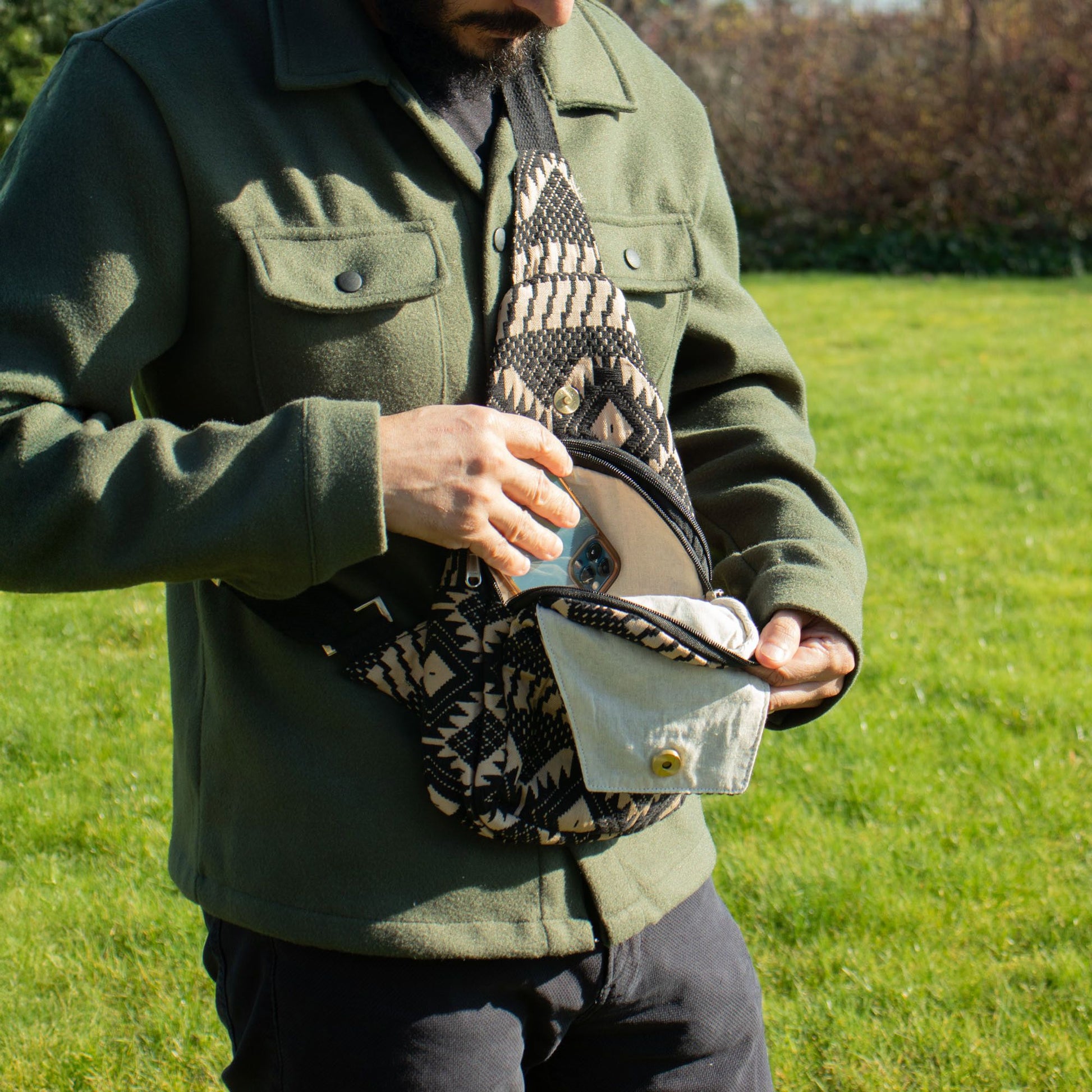 Bolso cruzado de tela negra y beige con diseño geométrico, ideal para estilo casual y actividades al aire libre.