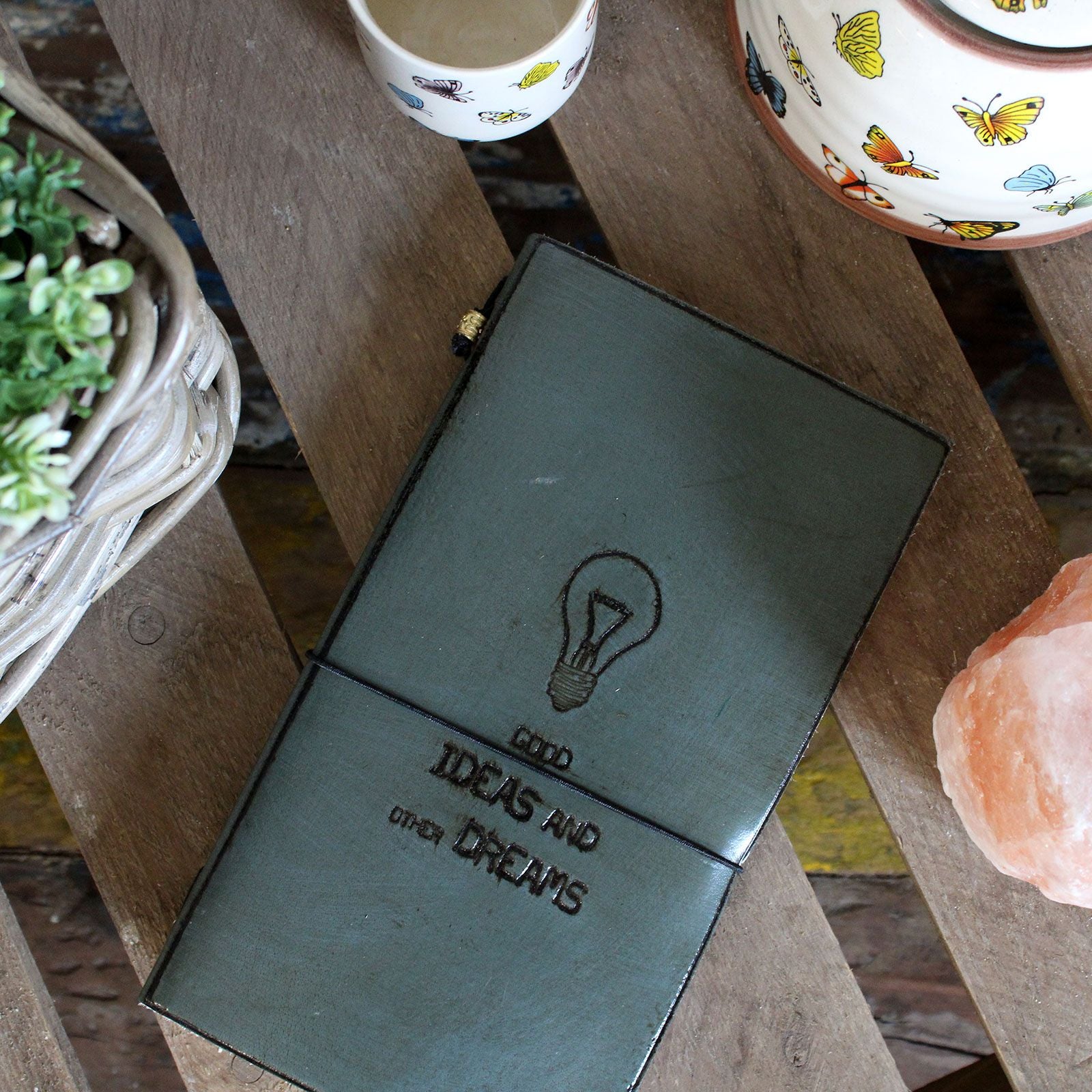 Cuaderno de tapa verde con grabado de bombilla, ideal para ideas y sueños. Material de cuero sintético.