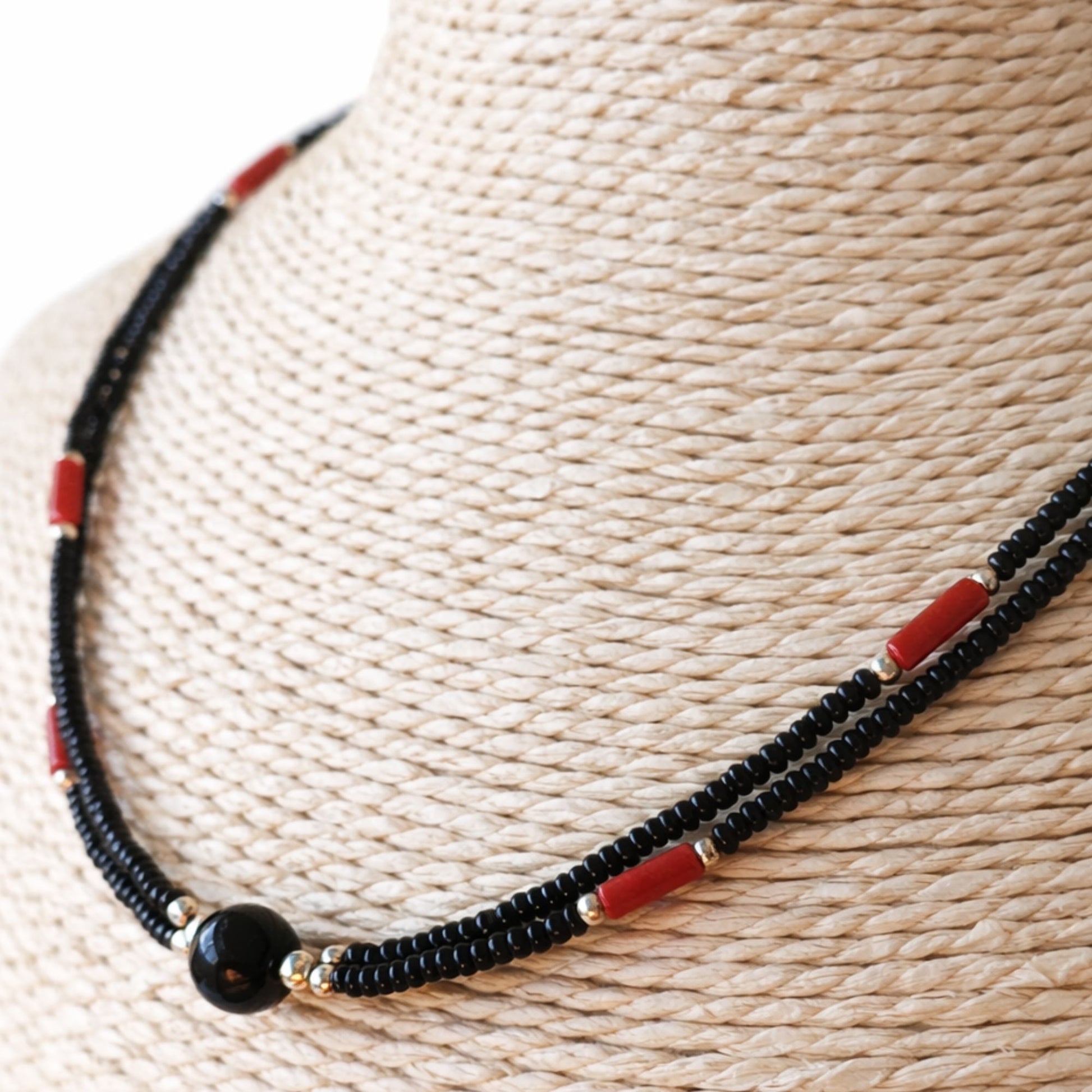 Collar de cuentas negras y rojas, con detalles dorados, estilo bohemio y moderno. Perfecto para ocasiones casuales.