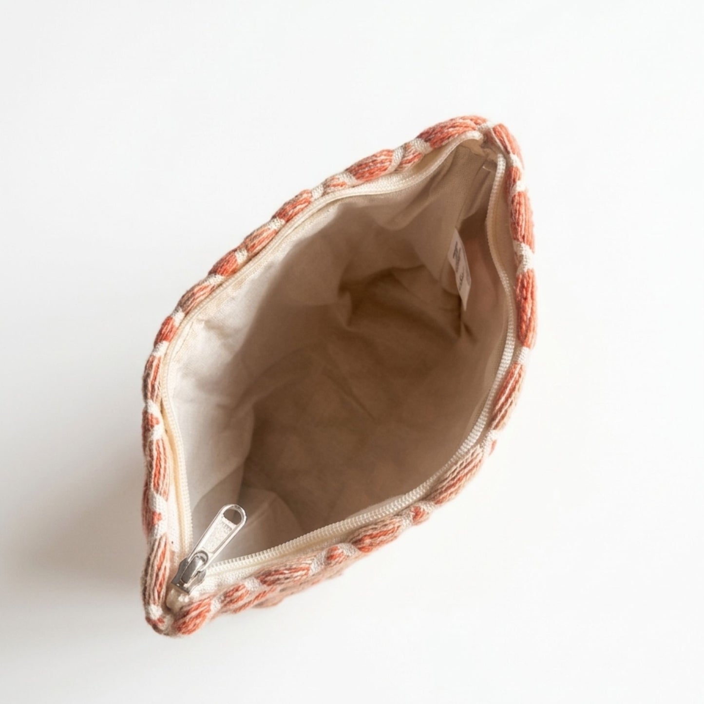 Bolso de mano tejido en tonos naranjas y beige, interior de tela suave, cierre de cremallera.