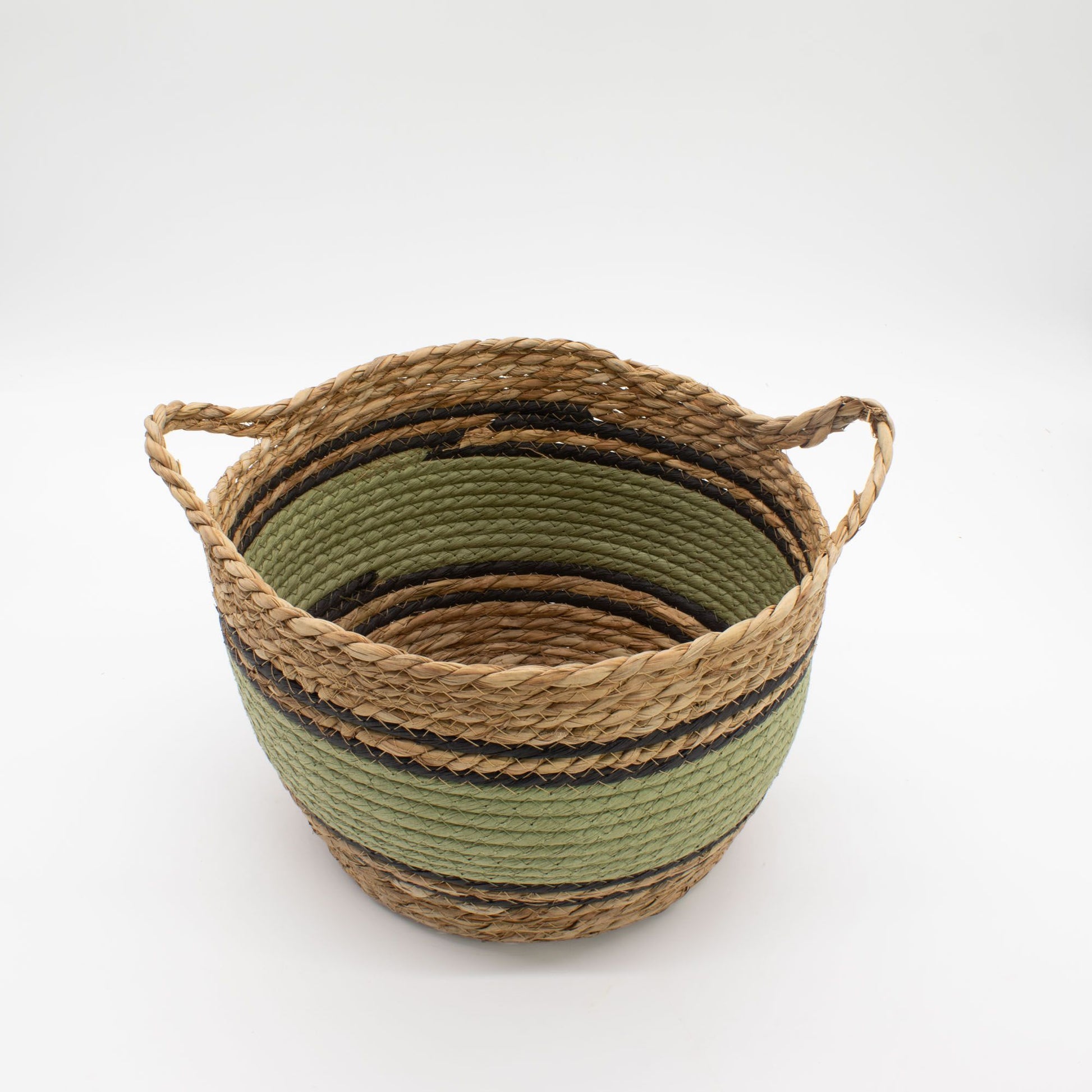 Cesta redonda tejida en pasto marino y algodón, con franjas naturales, verdes y negras, y dos asas laterales.