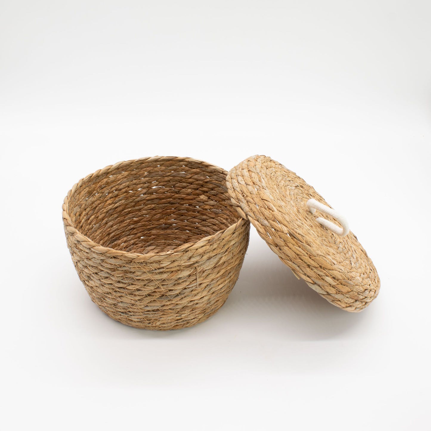 Cesta redonda de hierba marina trenzada color natural con tapa y asa de algodón, estilo artesanal y orgánico.