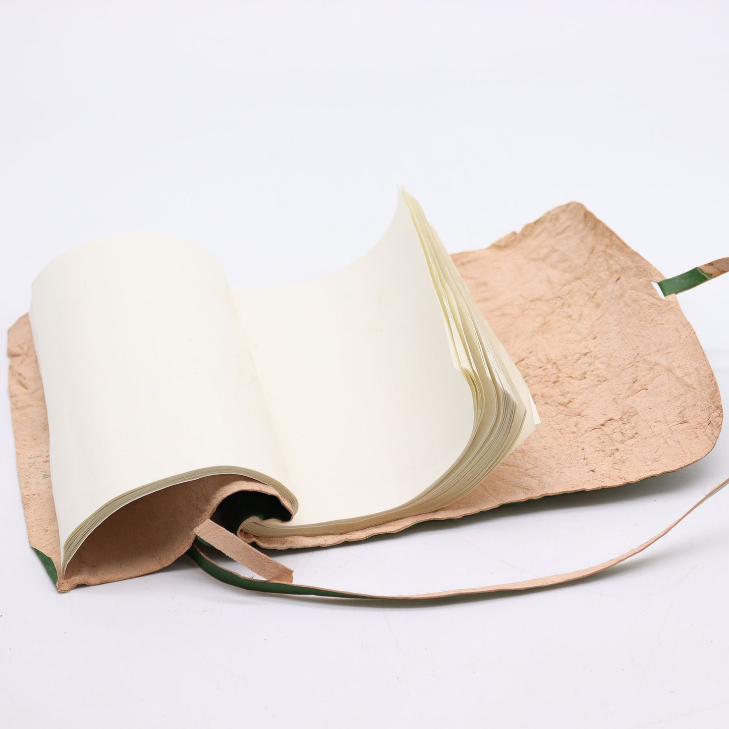Cuaderno artesanal de papel reciclado, color crema, con cubierta de yute natural y cinta verde. Ideal para escritura.