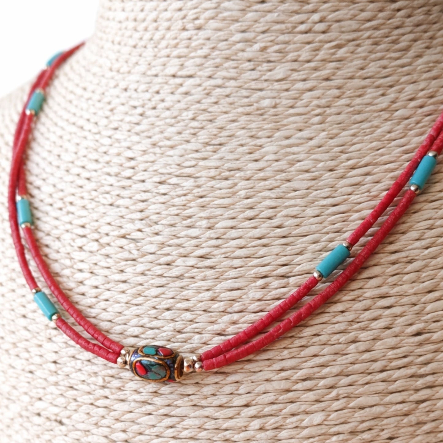 Collar de cuentas rojas y turquesas con detalle central dorado, estilo bohemio y materiales naturales.