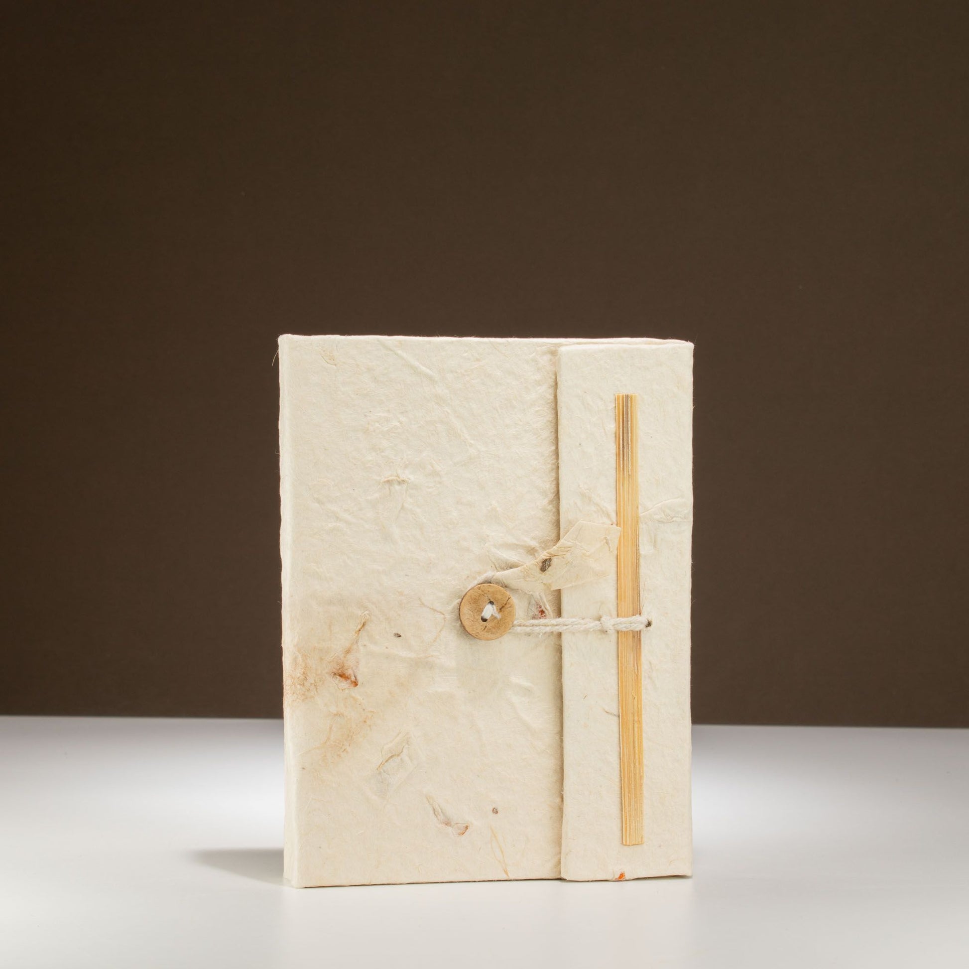 Cuaderno artesanal de papel reciclado blanco con cierre de madera y cuerda, estilo rústico y ecológico.