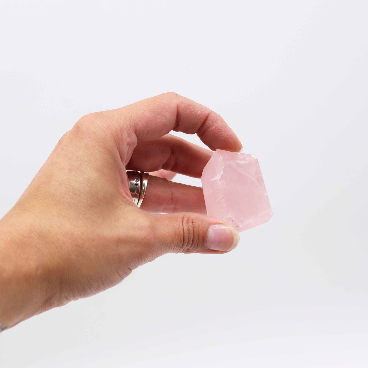 Cristal de cuarzo rosa en mano, forma rectangular, ideal para decoraciones y colecciones de minerales.