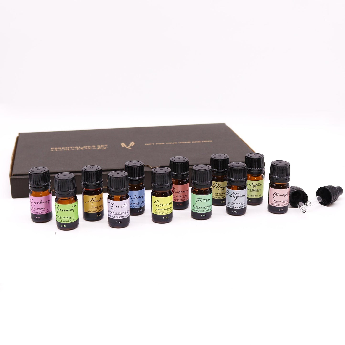 Set de 12 aceites esenciales en frascos de vidrio oscuro, variados colores de etiquetas, presentado en caja negra.
