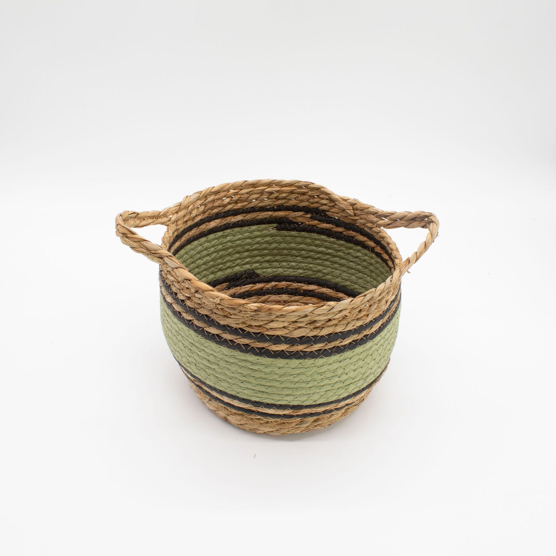 Cesta artesanal de pasto marino y algodón en tonos natural, verde y negro, con dos asas laterales sobre fondo blanco.