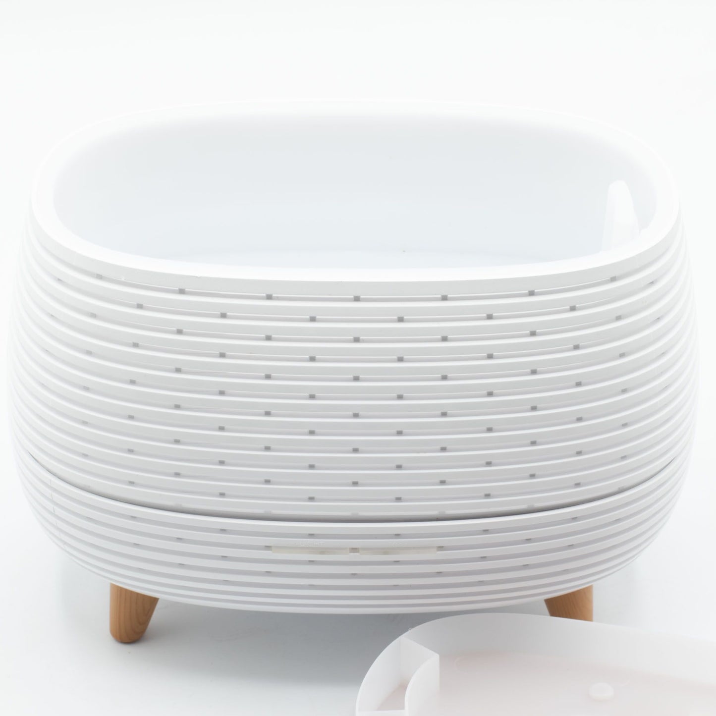 Maceta de plástico blanca con diseño estriado y patas de madera, ideal para plantas y decoración moderna.