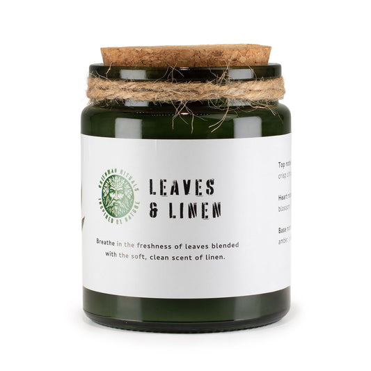 Vela verde en frasco de vidrio con tapa de corcho, aroma fresco a hojas y lino, decorativa y elegante.