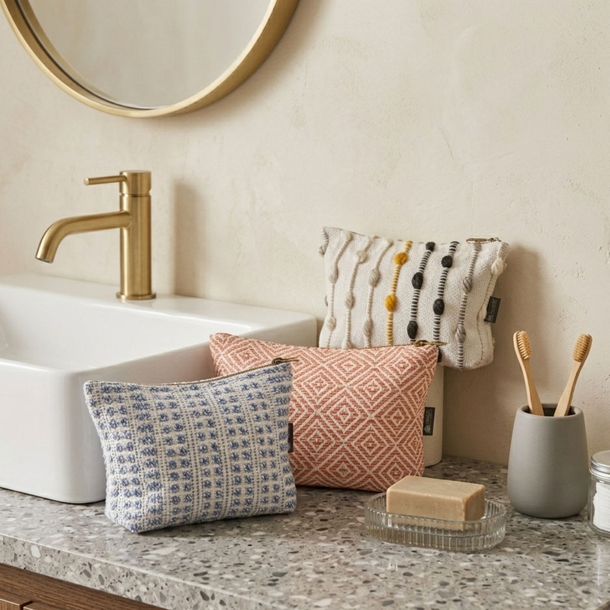 Cojines decorativos en tonos azul, naranja y beige, tejidos con patrones geométricos y texturas, ideales para el baño.