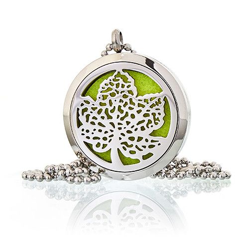 Collar de metal plateado con colgante de hoja y base verde, estilo moderno y elegante.
