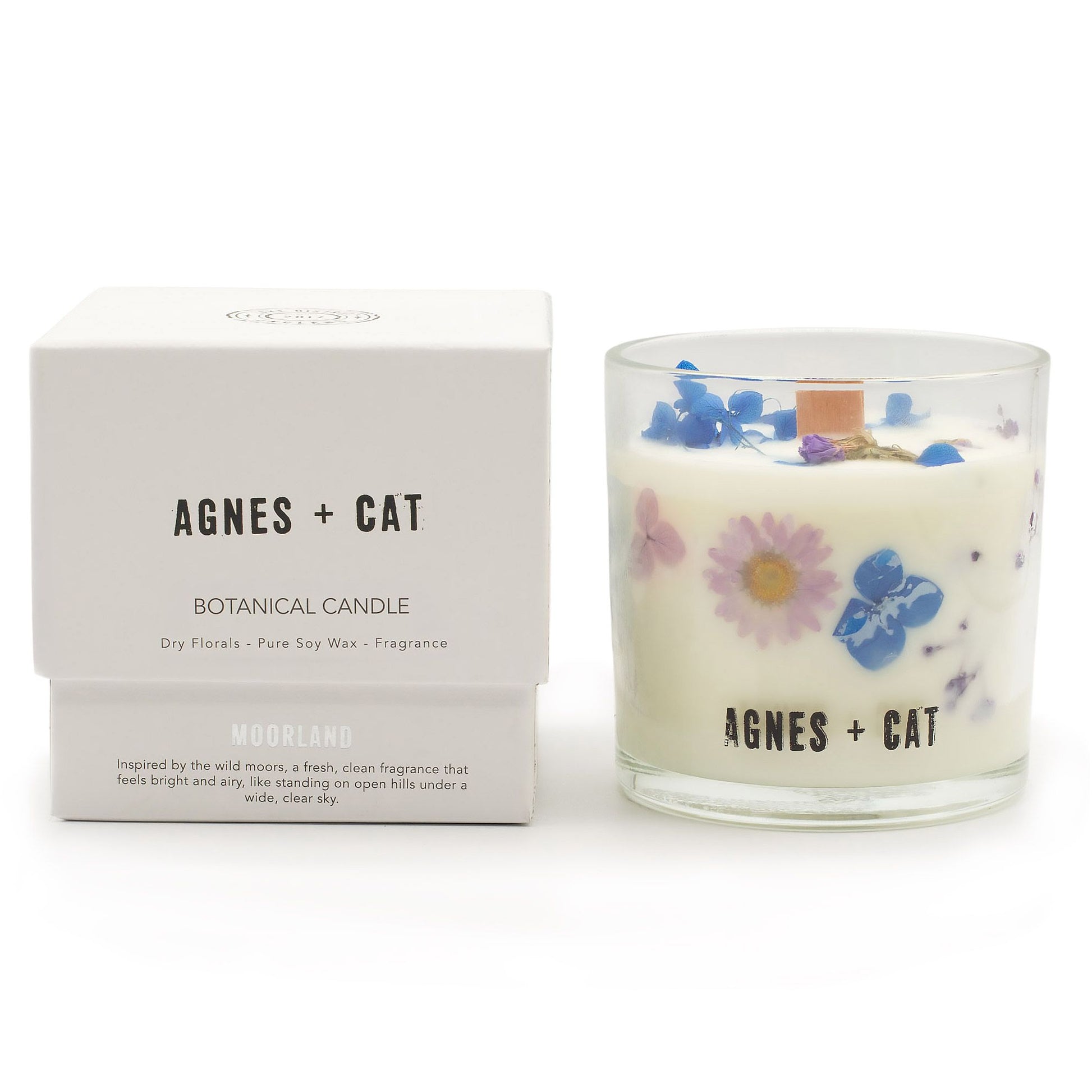 Vela botánica de soja pura con flores secas, aroma fresco, envase de vidrio transparente, caja blanca.