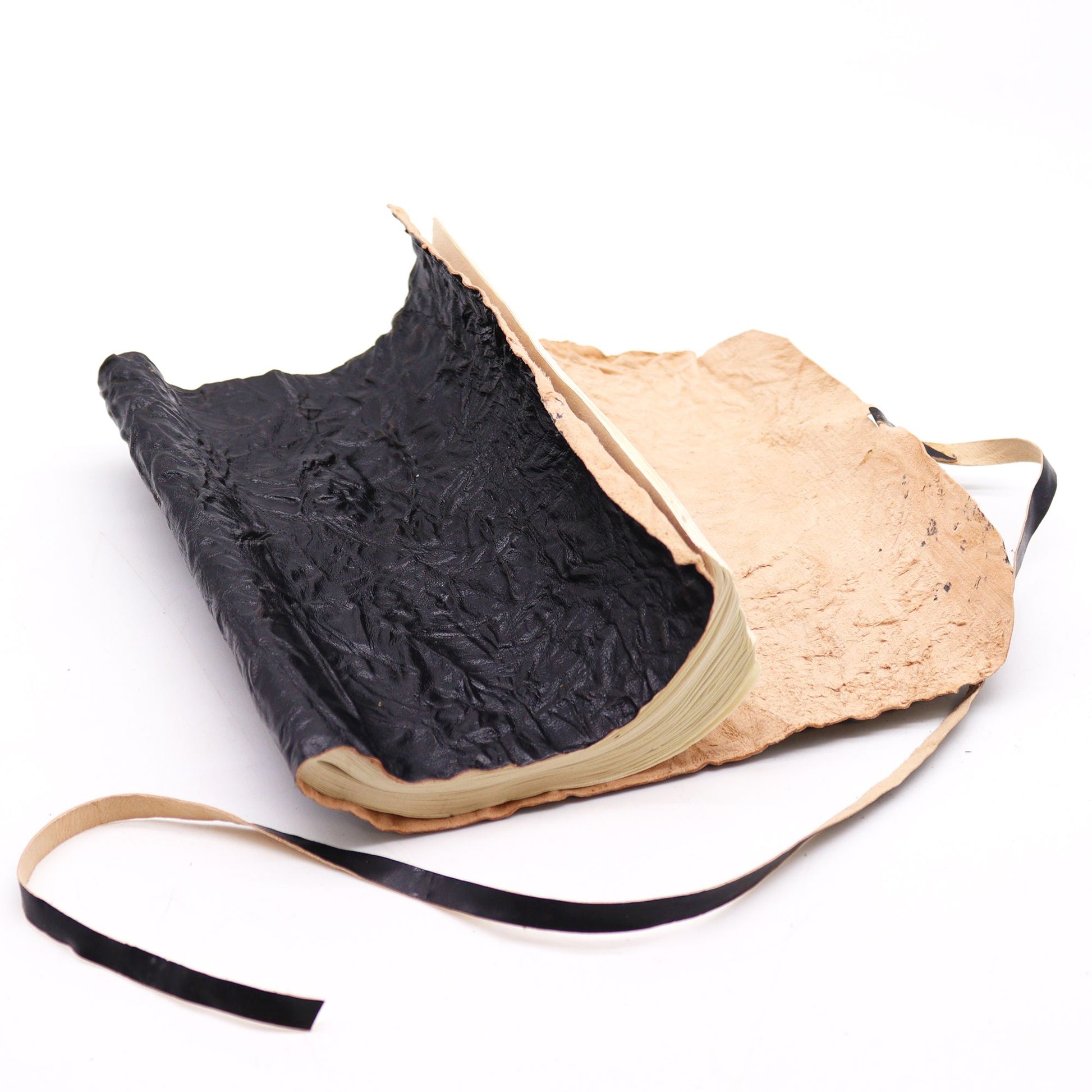 Cuaderno artesanal de piel negra y beige, con textura única y cinta negra, ideal para escritura creativa.