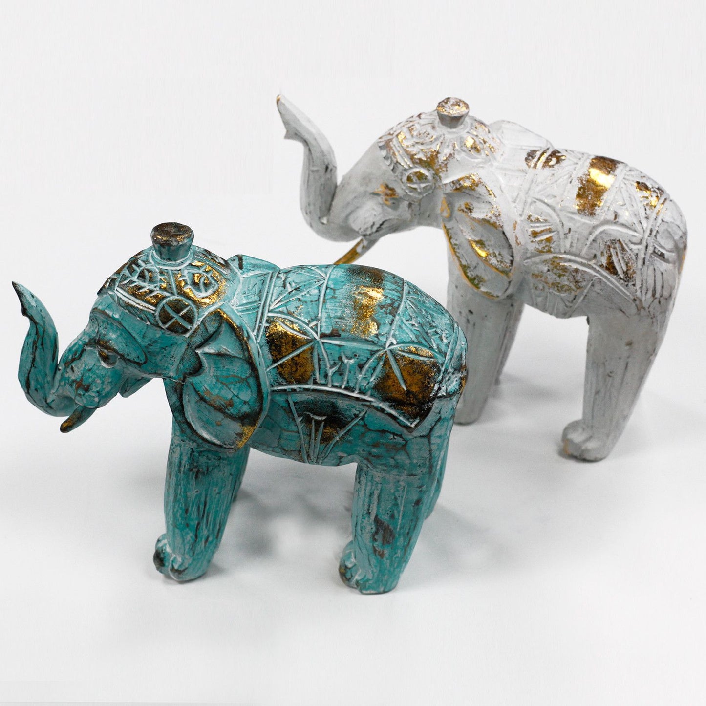Elefantes decorativos en cerámica, uno turquesa y otro blanco con detalles en dorado, estilo boho chic.