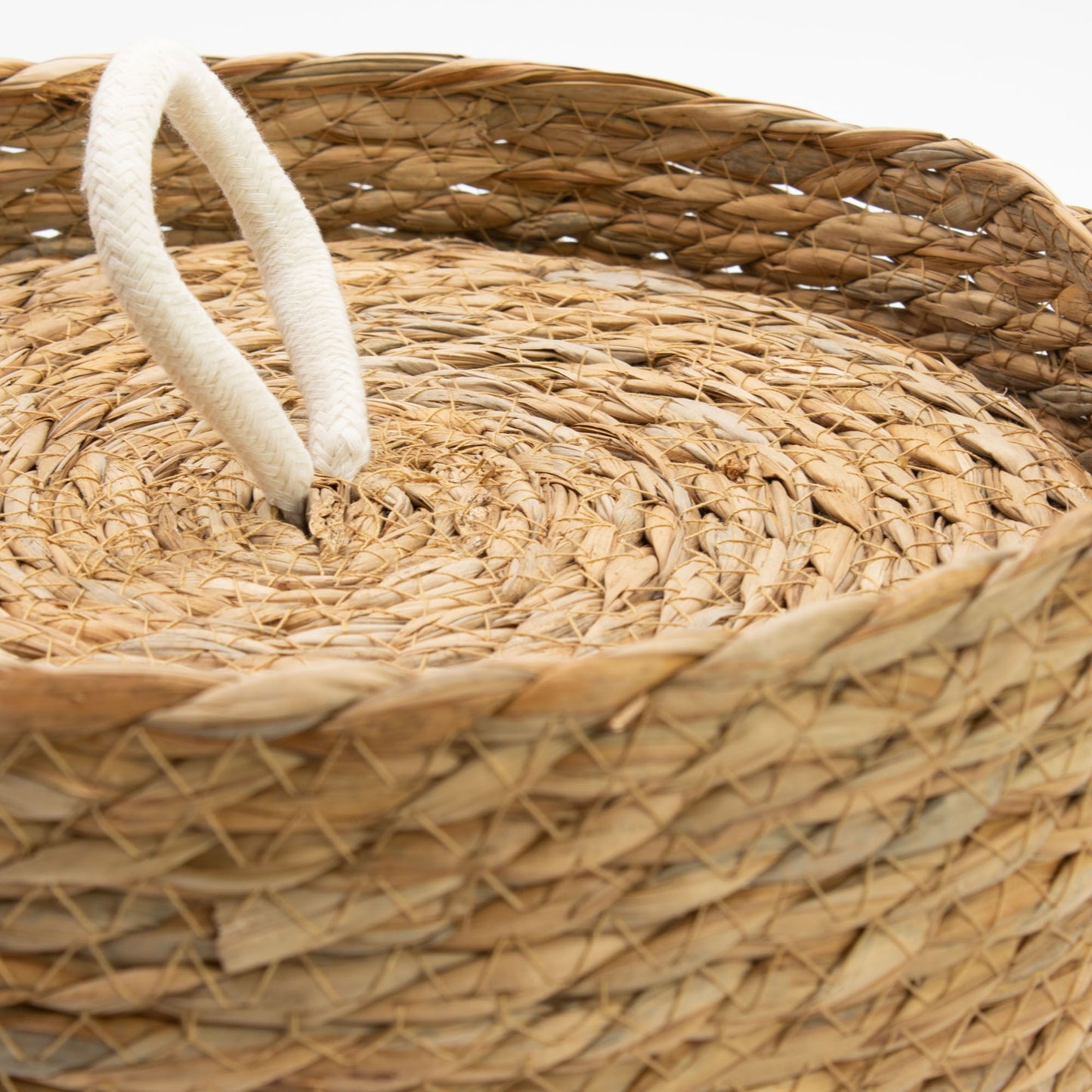 Cesta redonda de hierba marina tejida, color natural, con tapa y asa de cuerda blanca. Estilo artesanal y rústico.