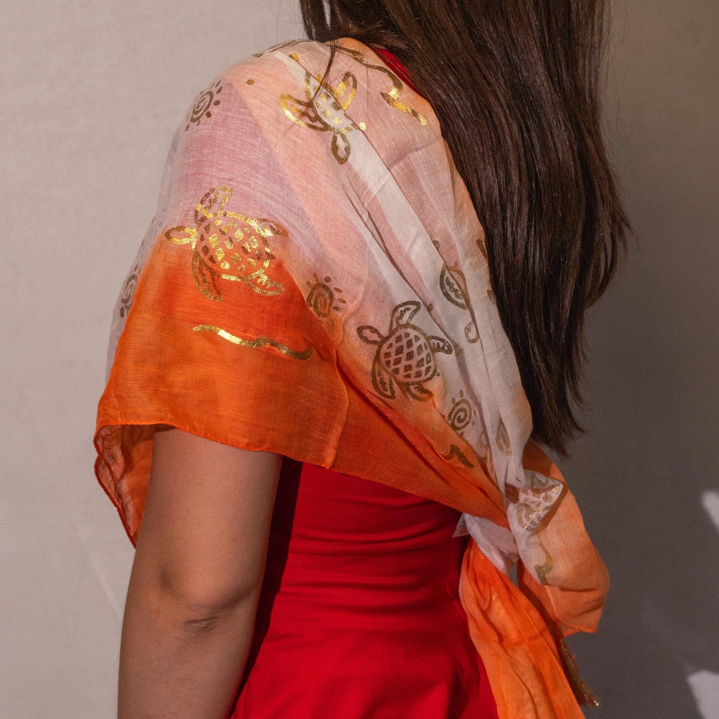 Chal de gasa naranja y blanco con estampado de tortugas doradas, ideal para un look elegante y veraniego.