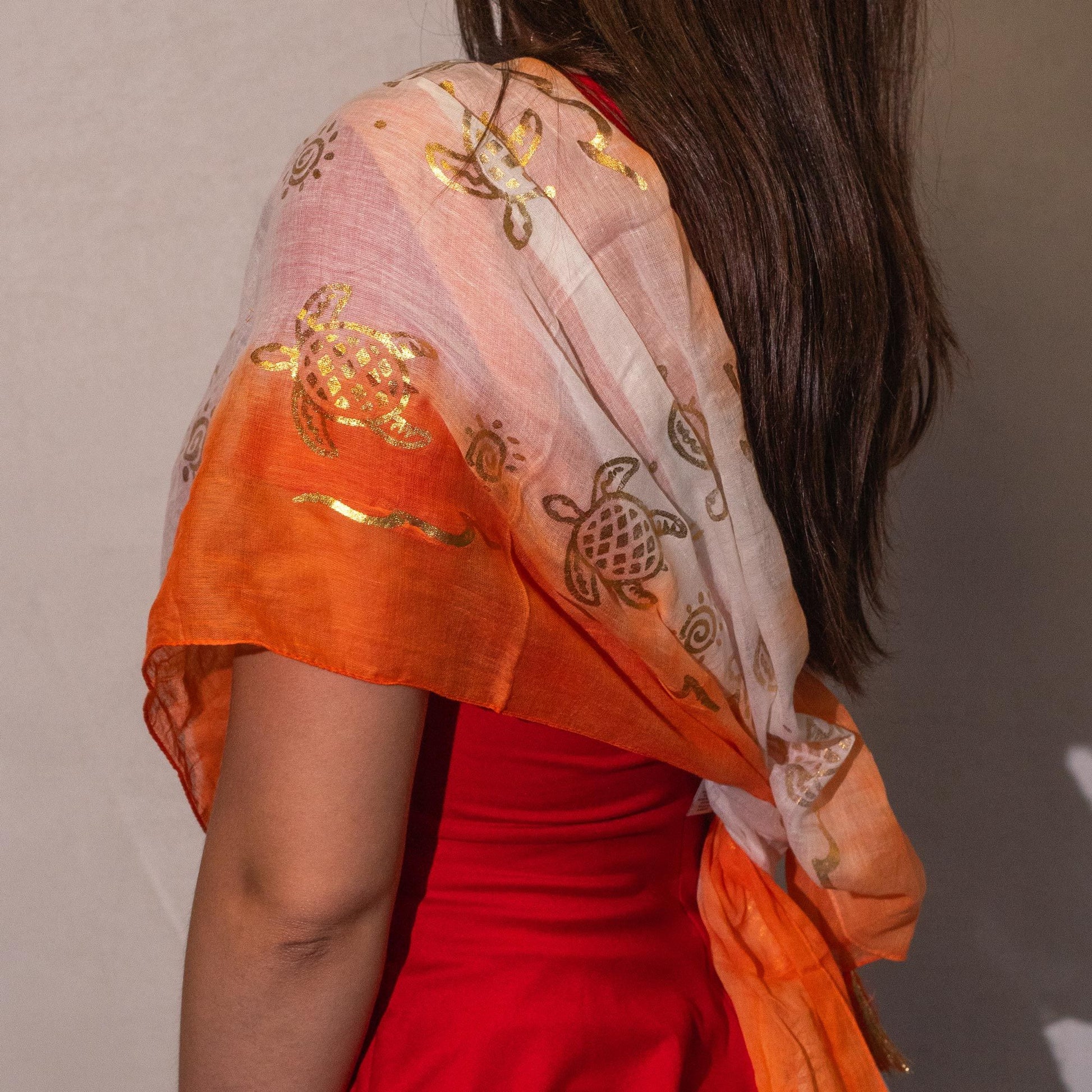 Chal de gasa naranja y blanco con estampado de tortugas doradas, ideal para un look elegante y veraniego.