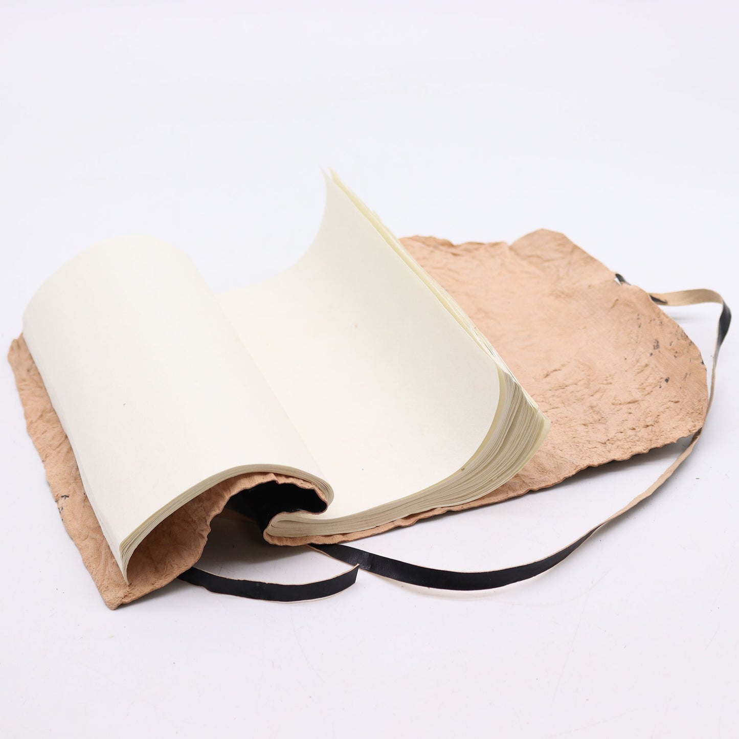 Cuaderno rústico de papel reciclado con cubierta de cartón marrón y cintas negras, estilo ecológico y artesanal.