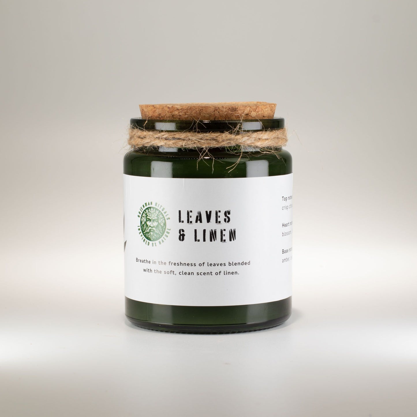 Vela aromática verde en frasco de vidrio con tapa de madera, fragancia a hojas y lino.