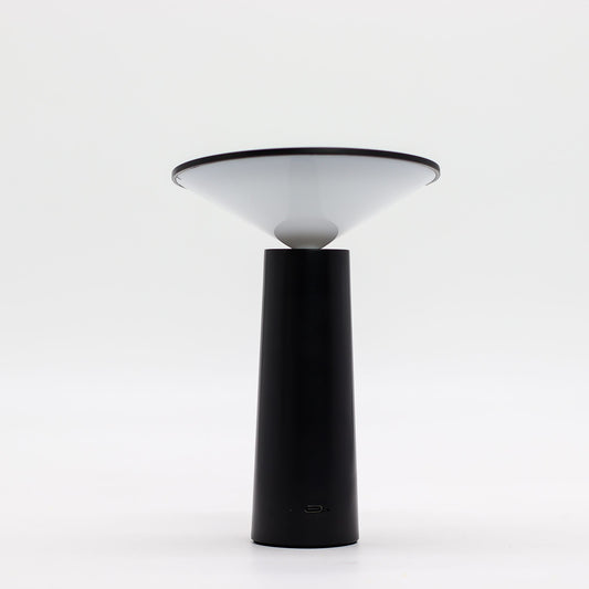 Lámpara de mesa tipo hongo, base cilíndrica negra y pantalla cónica blanca con puerto USB-C, diseño minimalista.