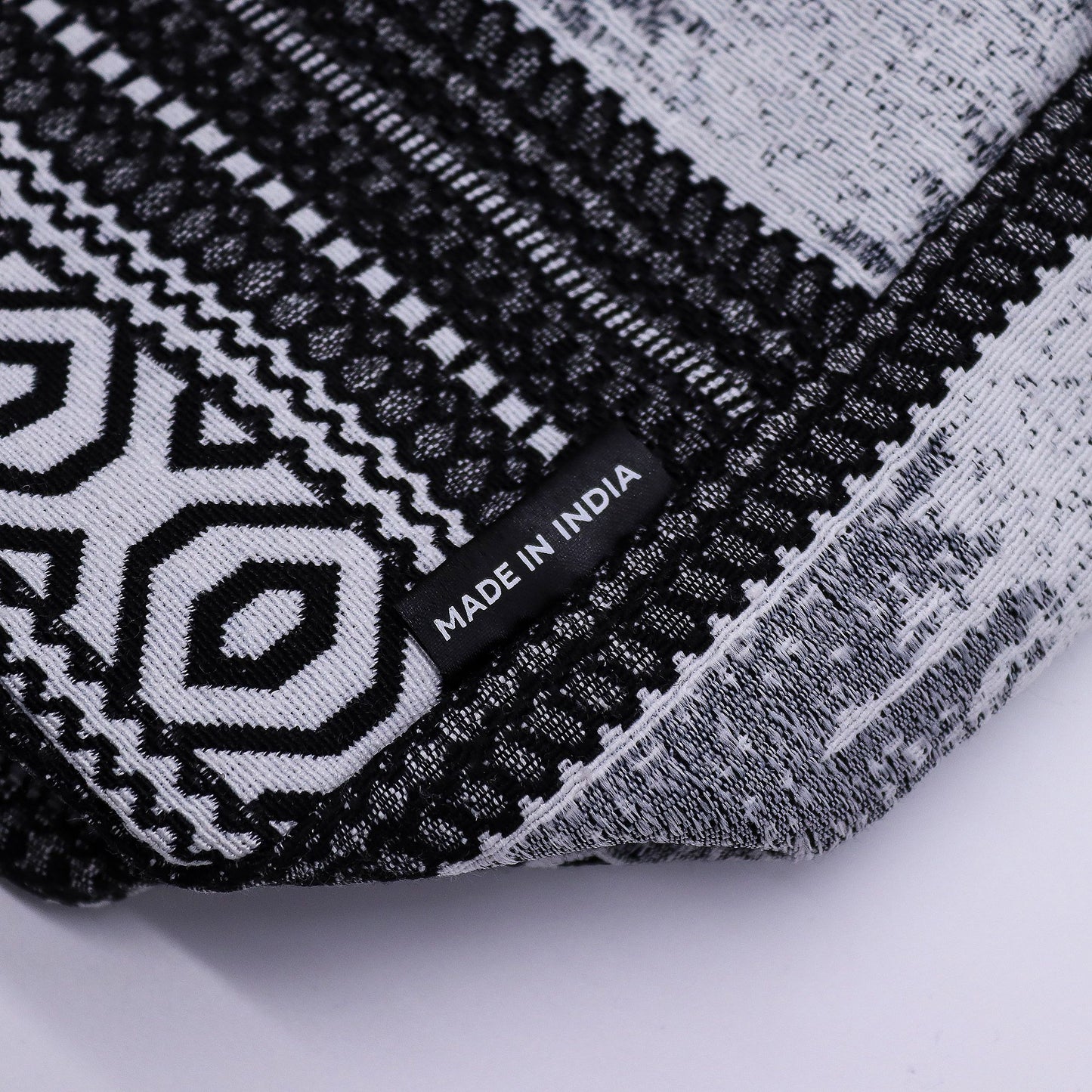 Chal negro y blanco con diseño geométrico, fabricado en India, ideal para estilo bohemio y casual.