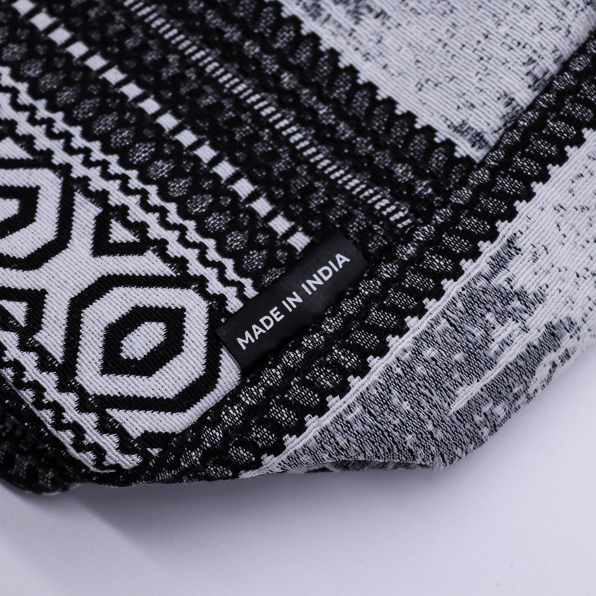 Chal negro y blanco con diseño geométrico, fabricado en India, ideal para estilo bohemio y casual.