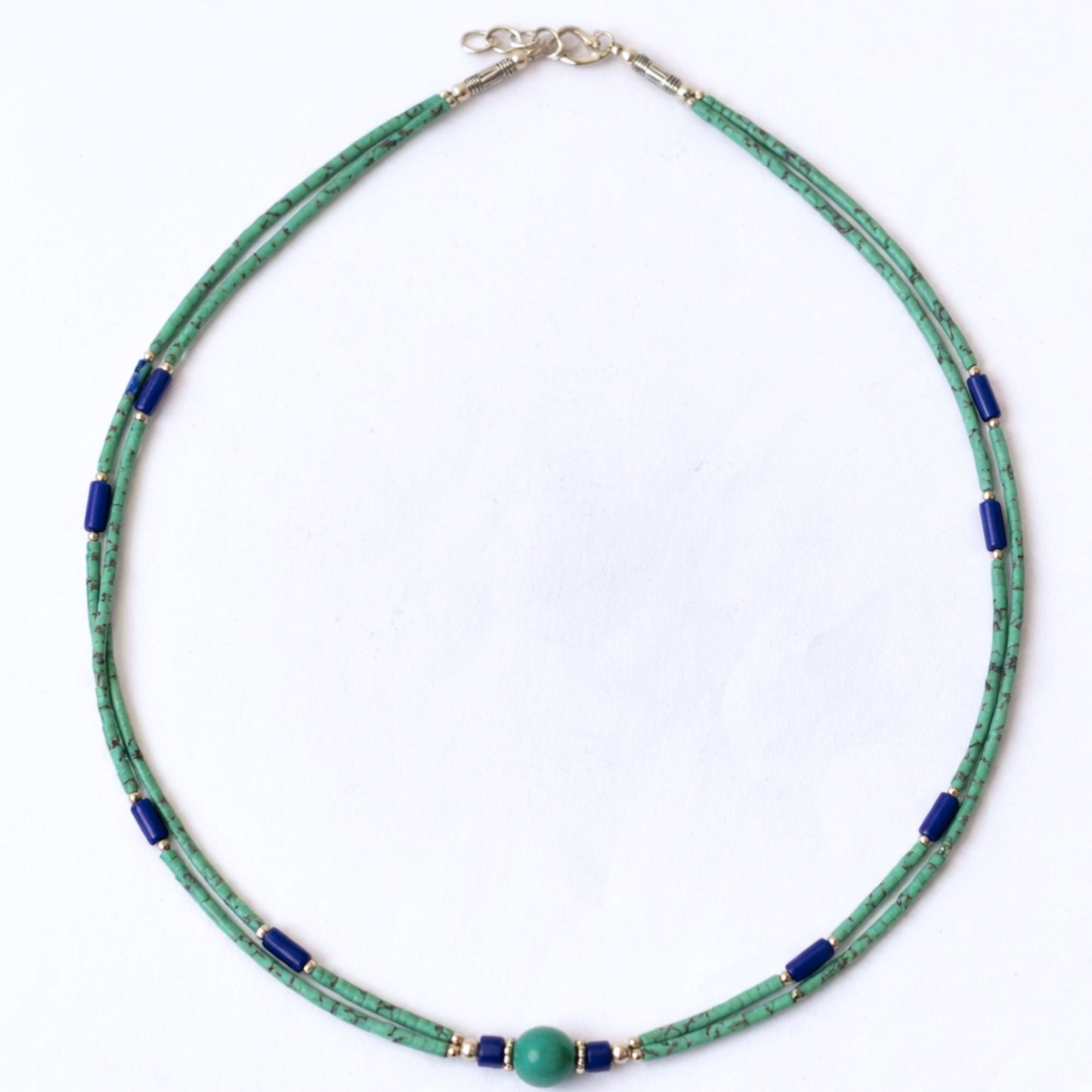 Collar de perlas verdes y azules, hecho de vidrio y metal, con cierre de plata. Estilo moderno y elegante.