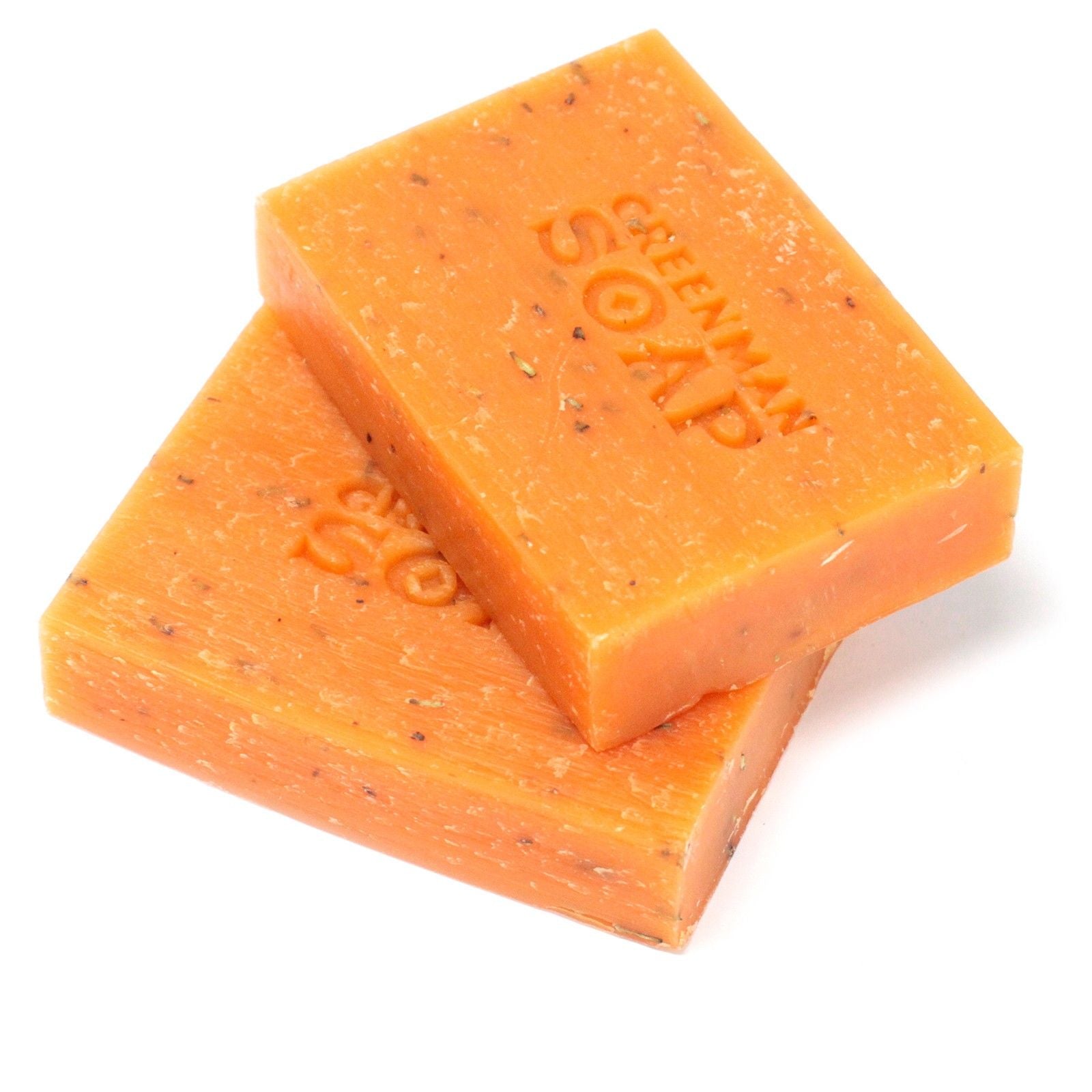 Dos pastillas de jabón naranja, artesanales, con motas exfoliantes y el sello "GREENMAN SOAP" grabado en la superficie.