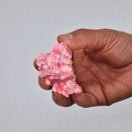 Cristal de cuarzo rosa brillante, textura rugosa, en mano, ideal para decoraciones y energías positivas.