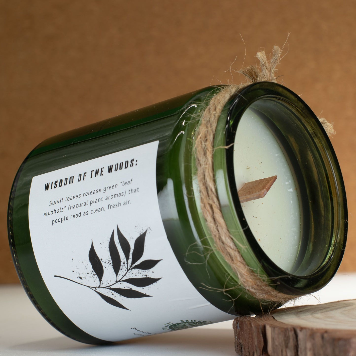 Vela verde "Wisdom of the Woods" en frascos de vidrio con aroma a hierbas y madera natural.
