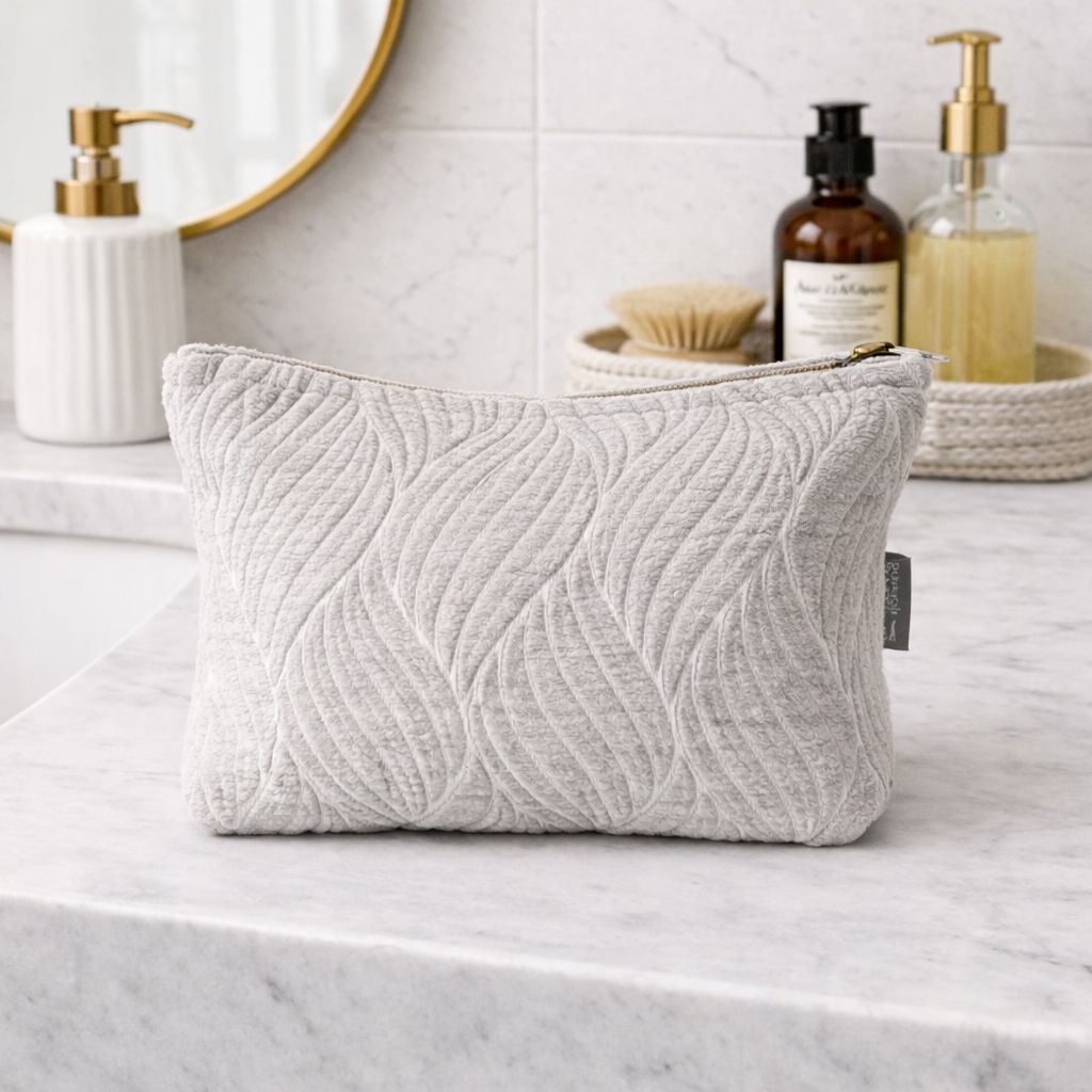 Neceser gris claro de tela suave con diseño de ondas, ideal para maquillaje y accesorios personales.